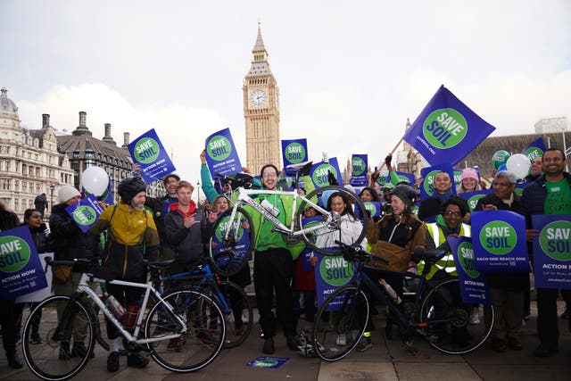 <p>Oscar Smith (centre, holding bike), 17, was welcomed by a group of Save Soil supporters in Parliament Square </p>