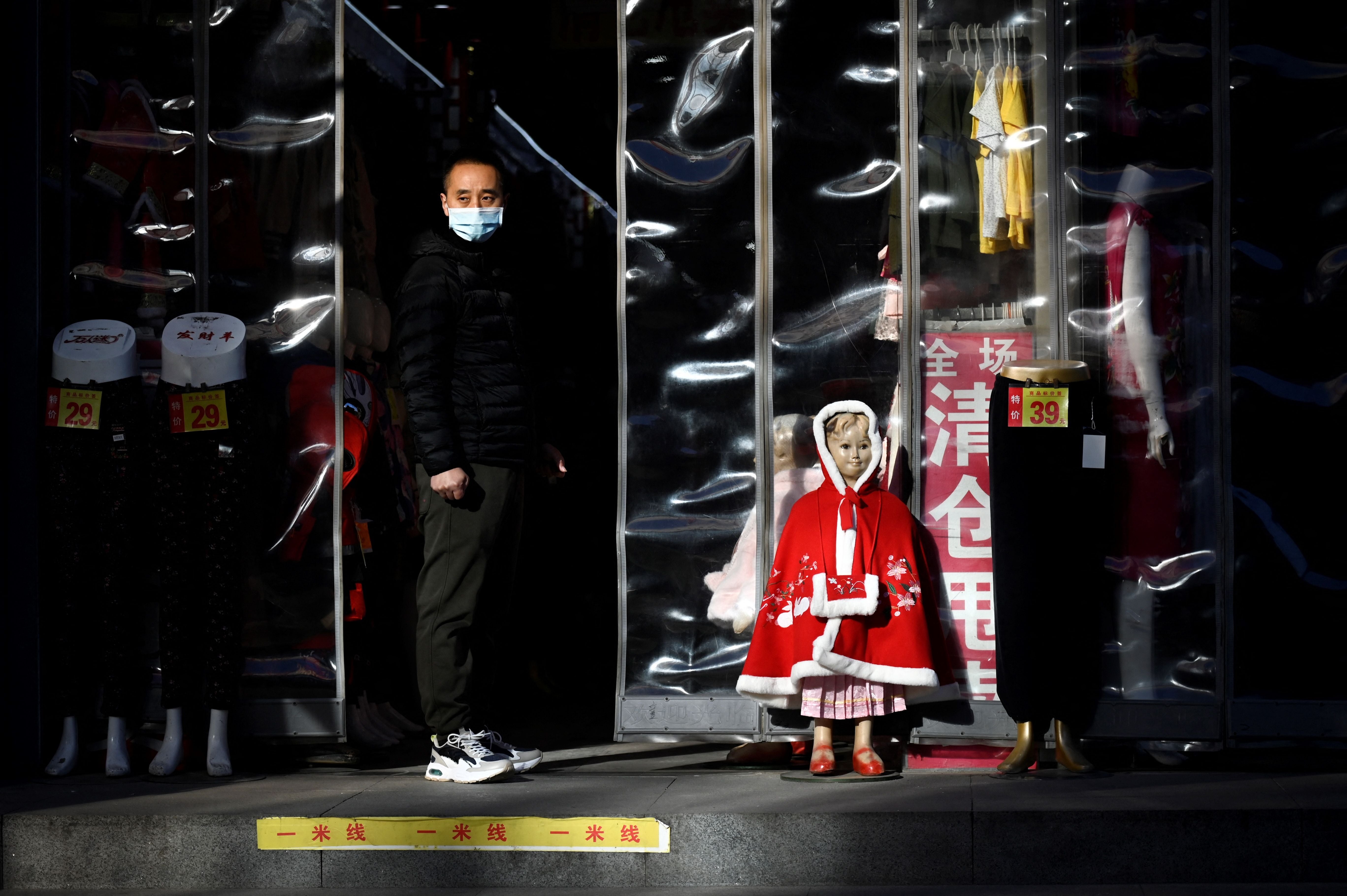 <p>A man watches from the entrance of a cloth shop along a business street in Beijing on Tuesday </p>