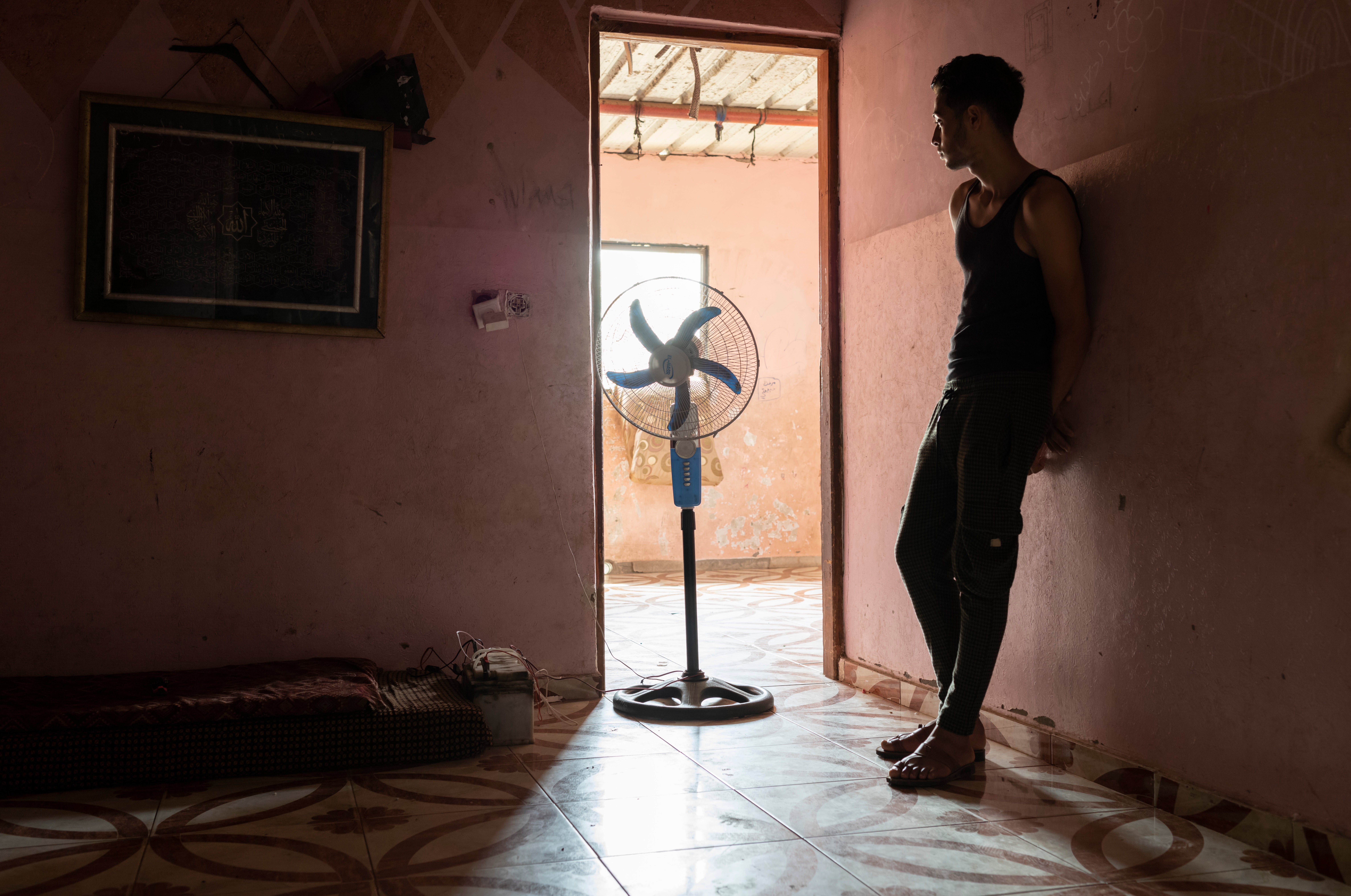 Mahmoud, 18, stands motionless in the humidity of his family home in Beit Lahia