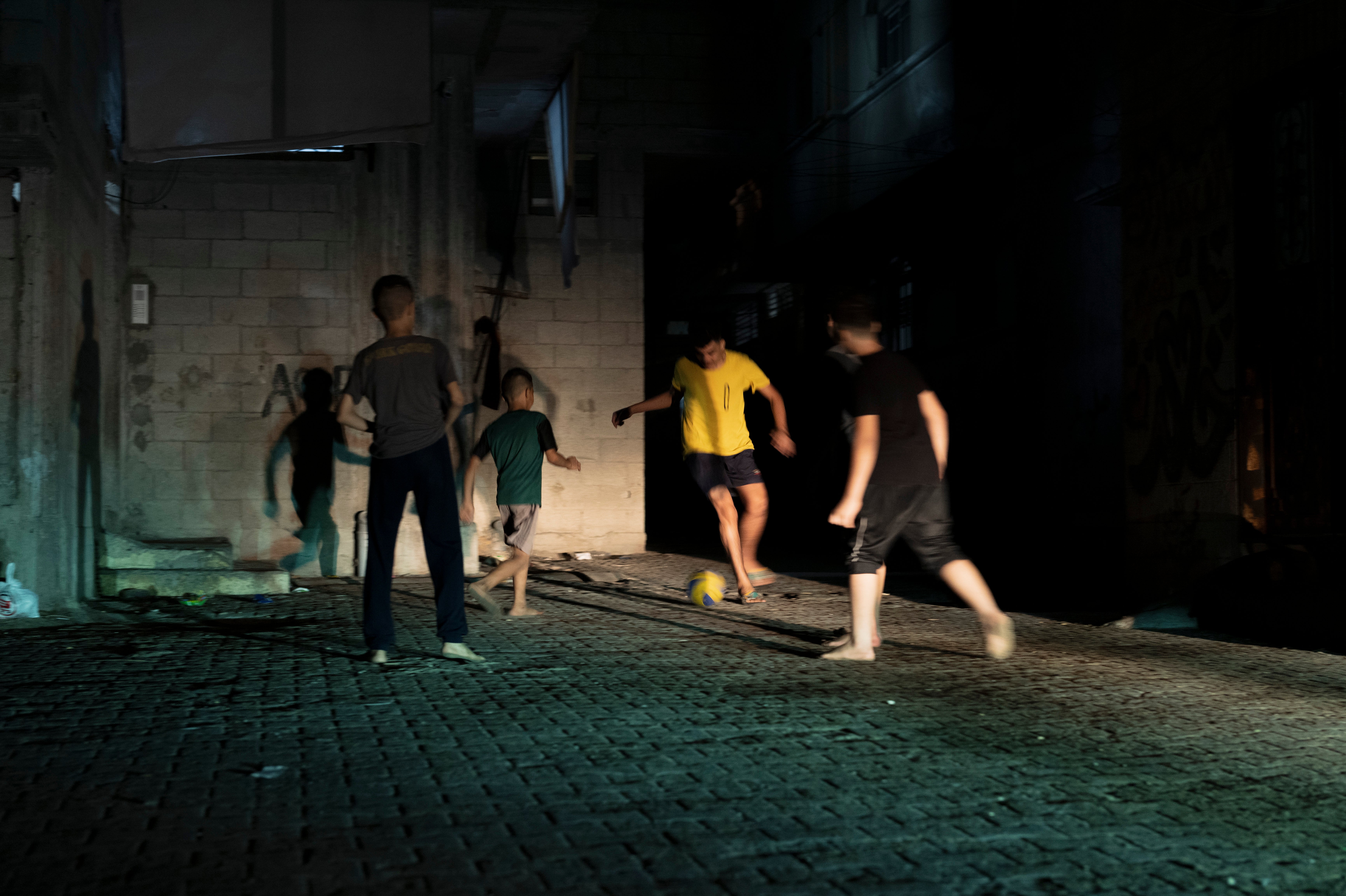 Children of Shati camp play football in the pitch-black streets and alleyways using only the headlights of passing cars