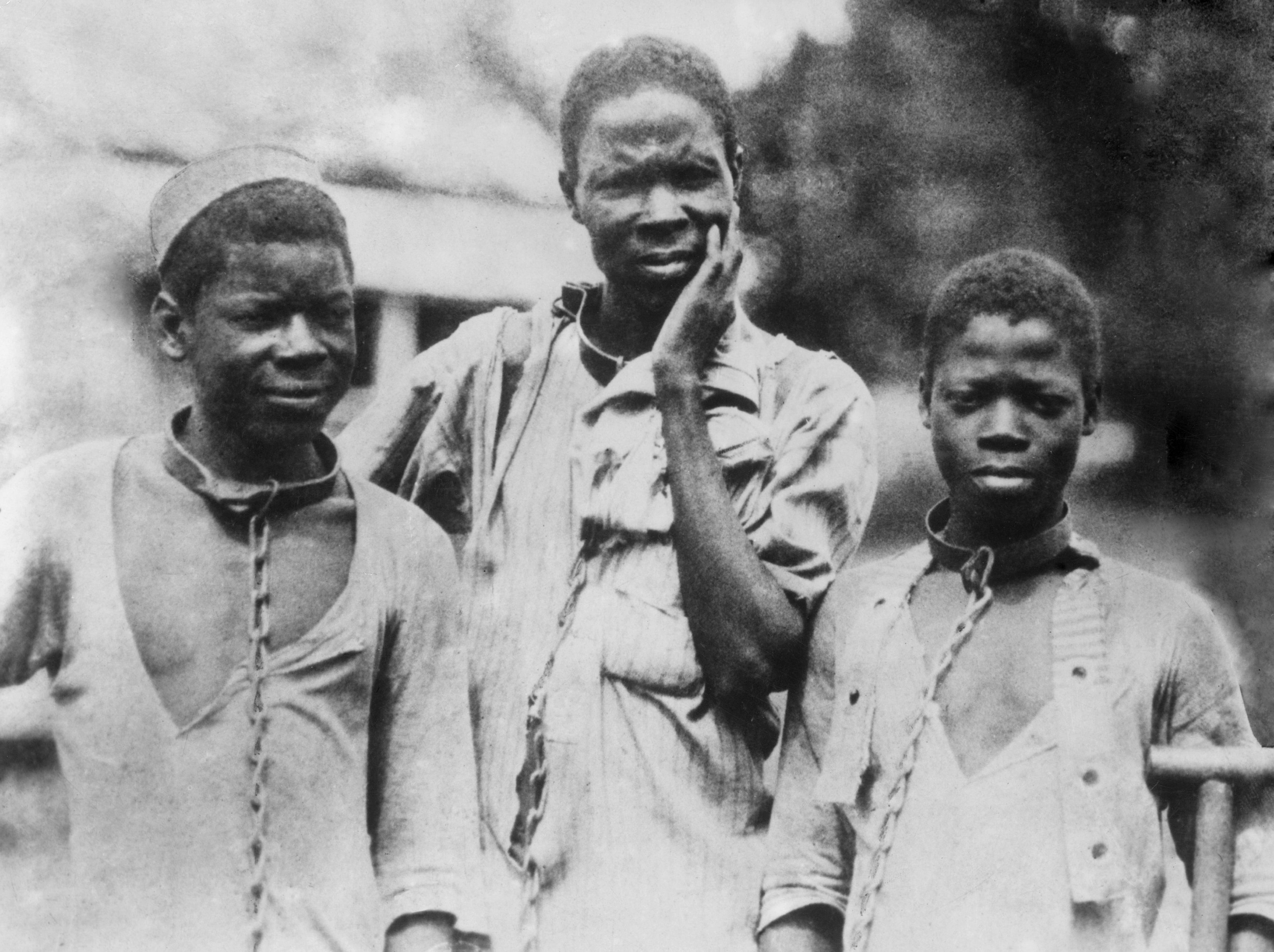 Three enslaved Black men from Ethiopia in iron collars and chains. Photograph taken around 1910