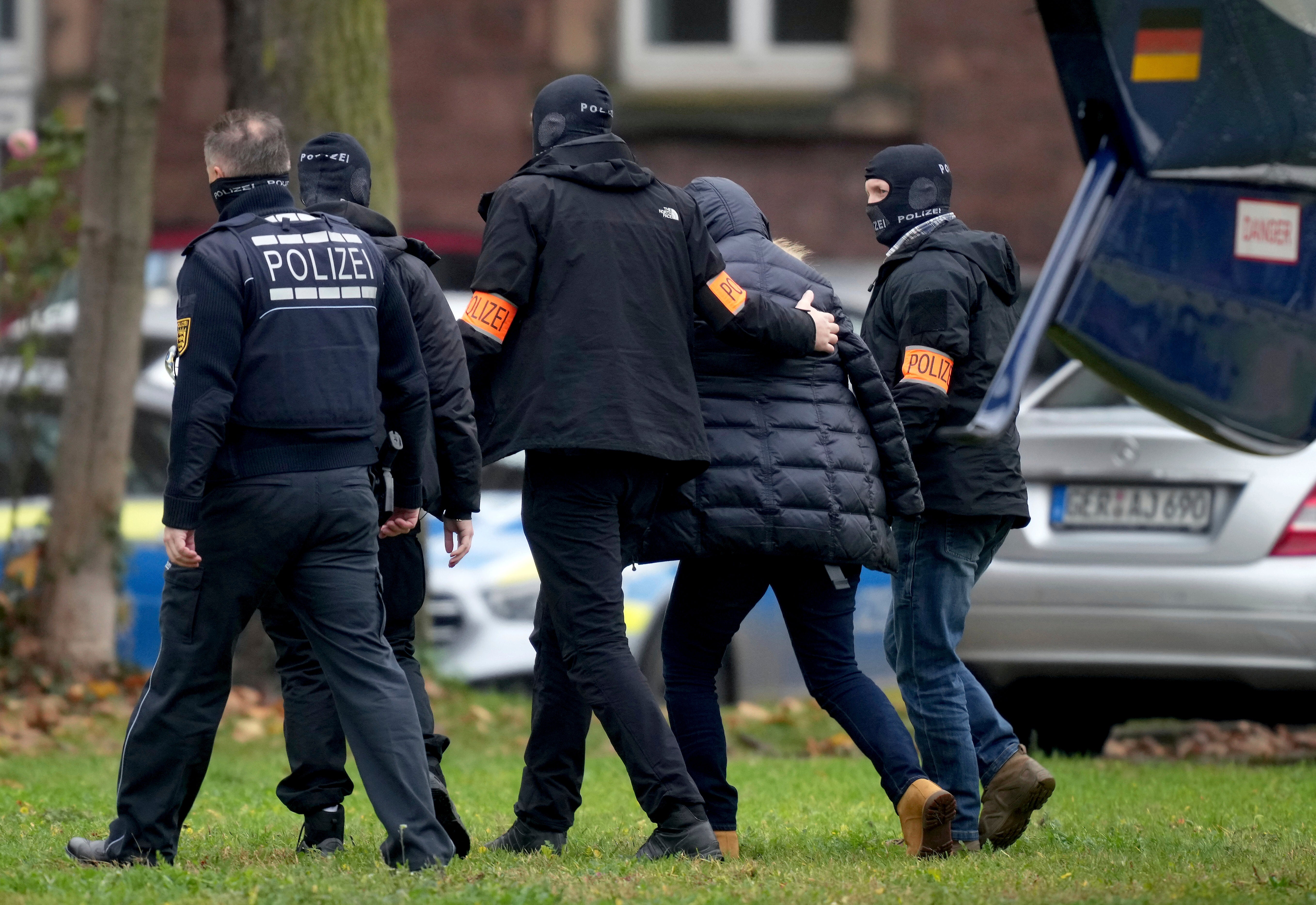 A suspect, second right, is escorted from a police helicopter by officers for questioning at the federal prosecutor’s office in Karlsruhe