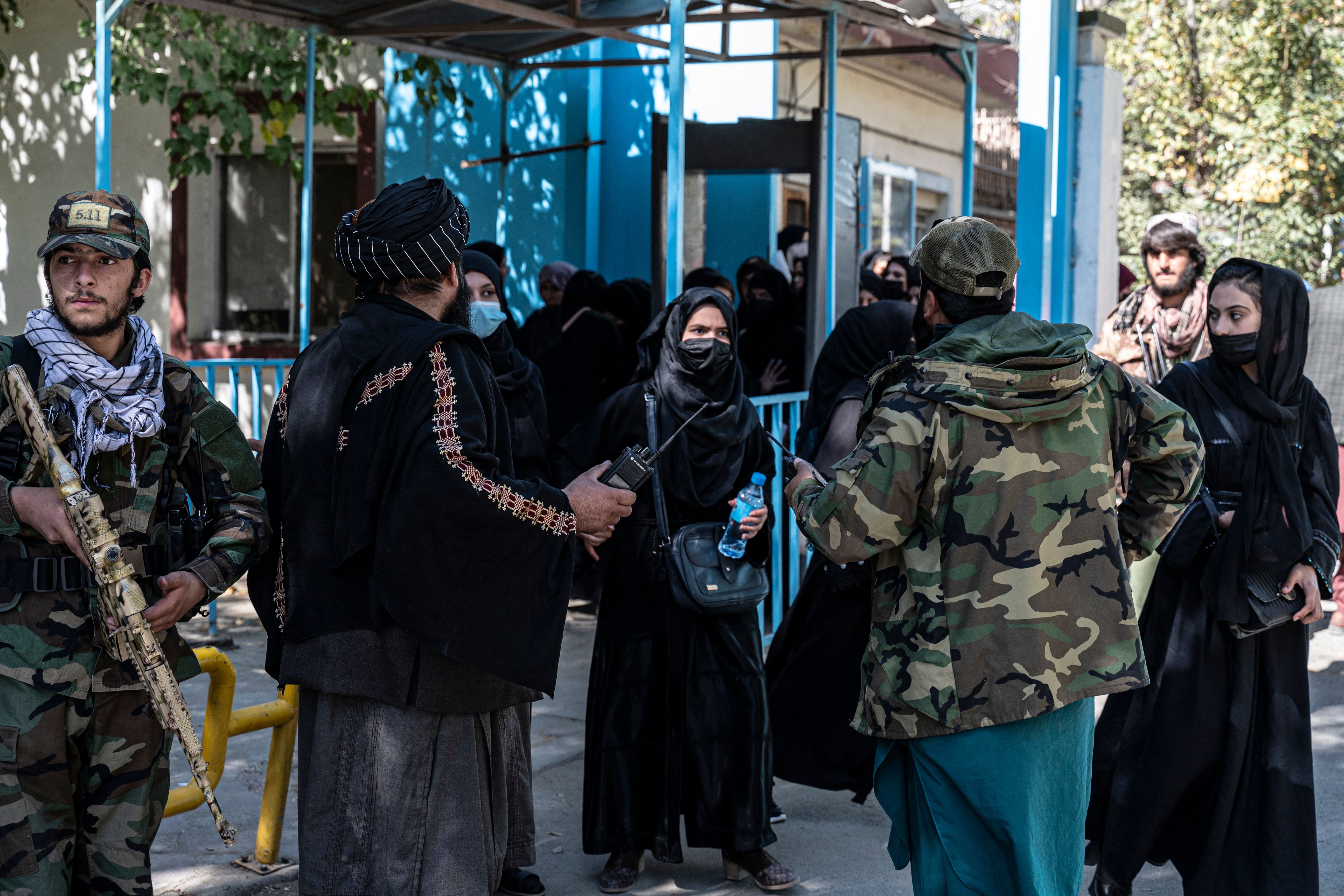 File: Taliban fighters stand guard as female students arrive for entrance exams at Kabul University in Kabul