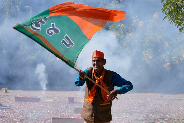 <p>A Bharatiya Janata party (BJP) supporter celebrates lead for the party in Gujarat state elections in Gandhinagar on 8 December 2022</p>