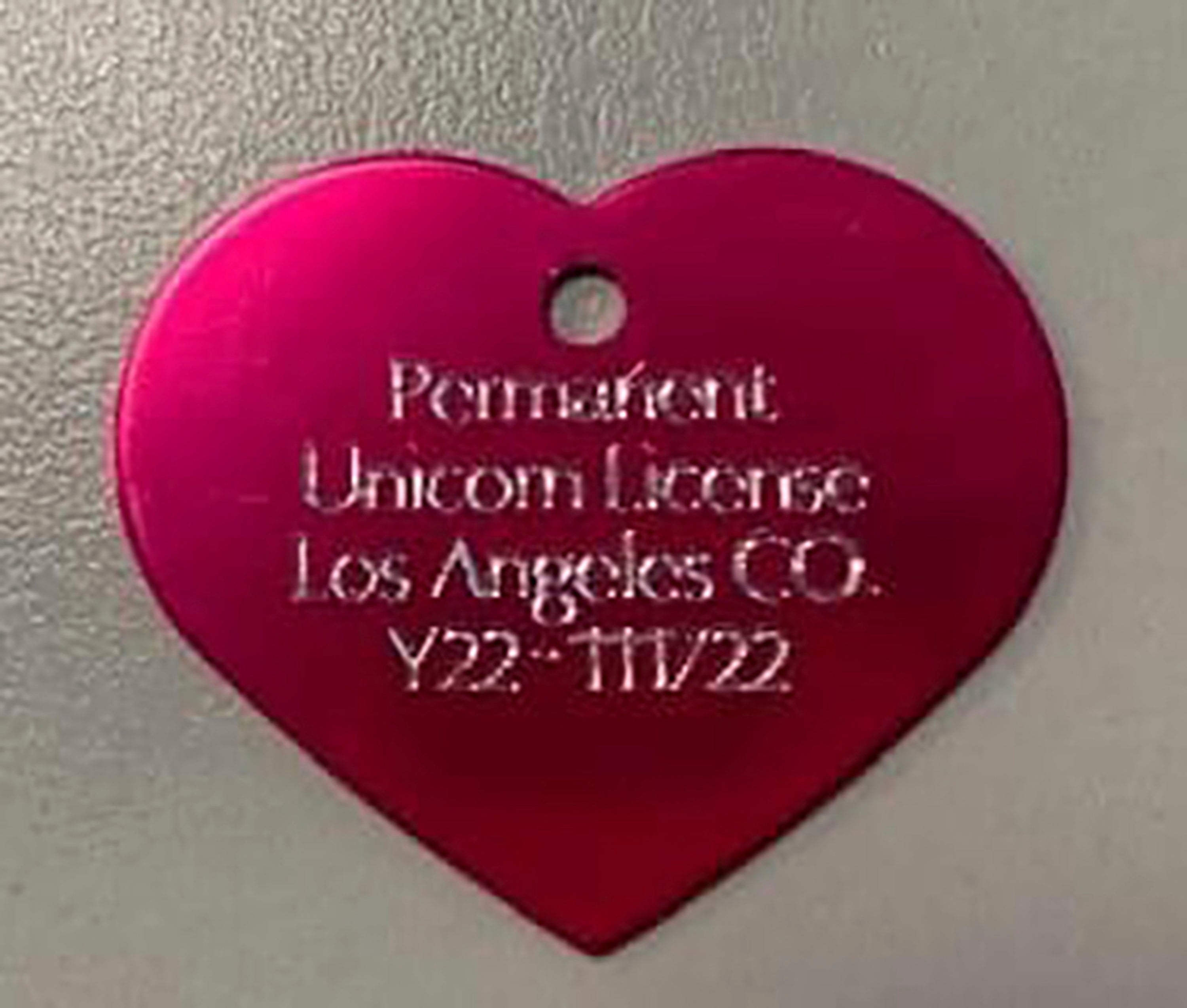 The heart-shaped, rose-colored metal tag with “Permanent Unicorn License” emblazoned on it