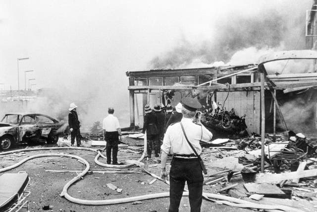 A dark mushroom cloud of smoke drifts across the centre of Belfast, as Firemen hose down the remains of Oxford Street bus station during the Troubles (PA)