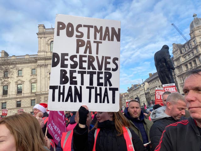 <p>Striking postal workers hold placard reading ‘Postman Pat deserves better than that’ at Parliament Square rally</p>