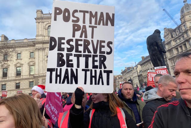 <p>Striking postal workers hold placard reading ‘Postman Pat deserves better than that’ at Parliament Square rally</p>