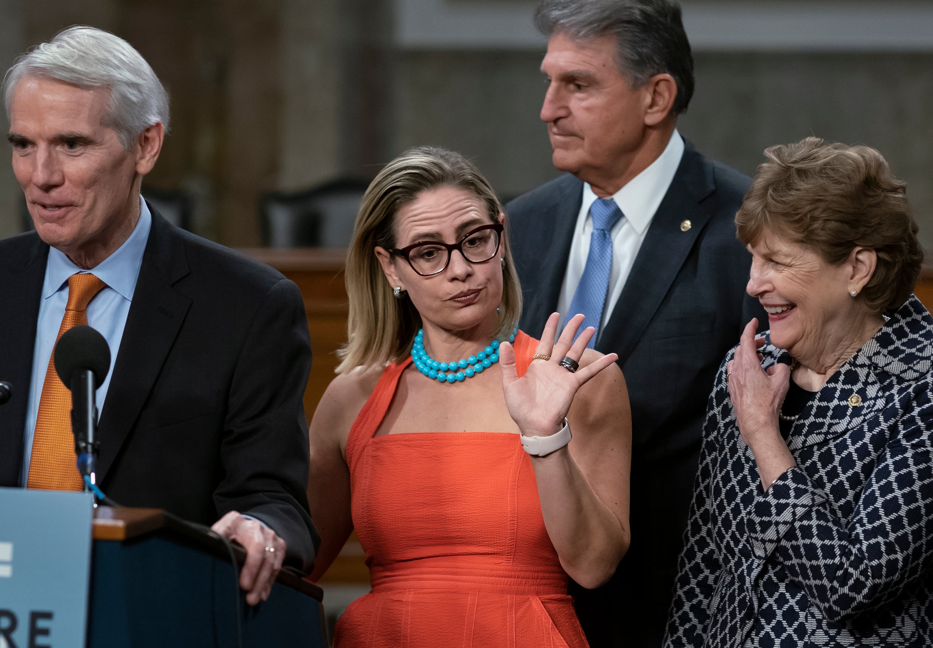 Kyrsten Sinema, with Joe Manchin standing behind her, attends a press conference in the Capitol