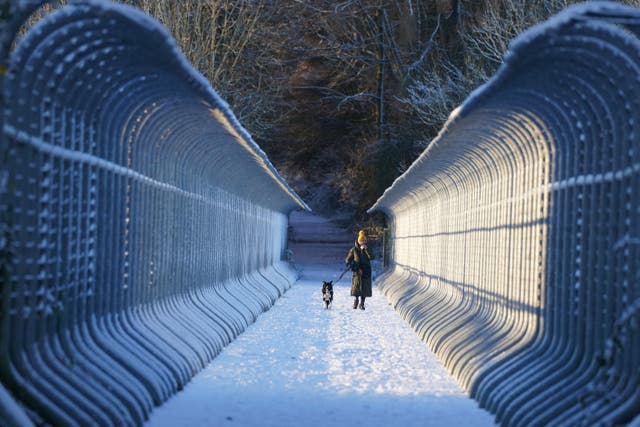 A woman walks her dog through snow over Castleside Viaduct in Durham. Parts of the UK are being hit by freezing conditions with the UK Health Security Agency (UKHSA) issuing a Level 3 cold weather alert covering England until Monday and the Met Office issuing several yellow weather warnings for snow and ice in parts of the UK over the coming days. Picture date: Friday December 9, 2022.