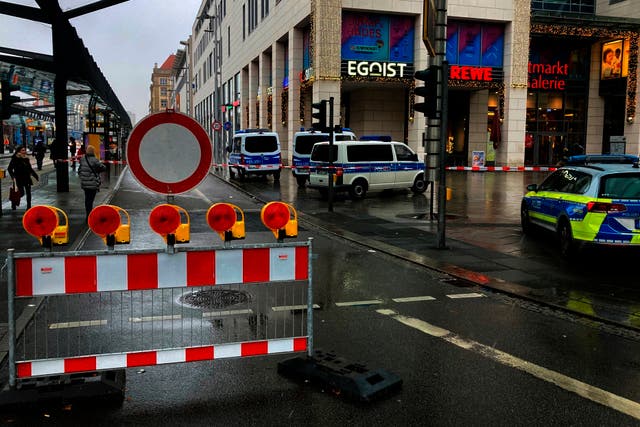 <p>Police vehicles are parked around a cordoned off area at the Altmarktgalerie after a hostage situation in Dresden, German</p>