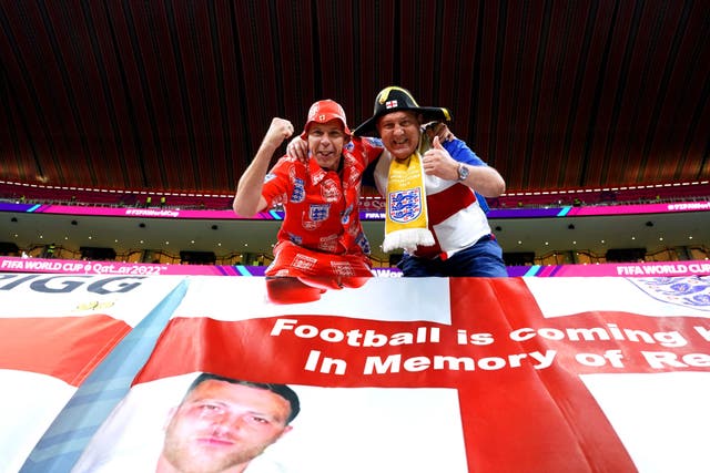 Mark Trigg (left), 48, from Derby and civil servant Garford Beck, 60, from London, in the stands ahead of the Fifa World Cup match between England and Senegal at the Al-Bayt Stadium in Al Khor, Qatar, with a flag made in memory of Reece Newcombe, 31, who died after he was stabbed on Richmond Bridge last month (Martin Rickett/PA)