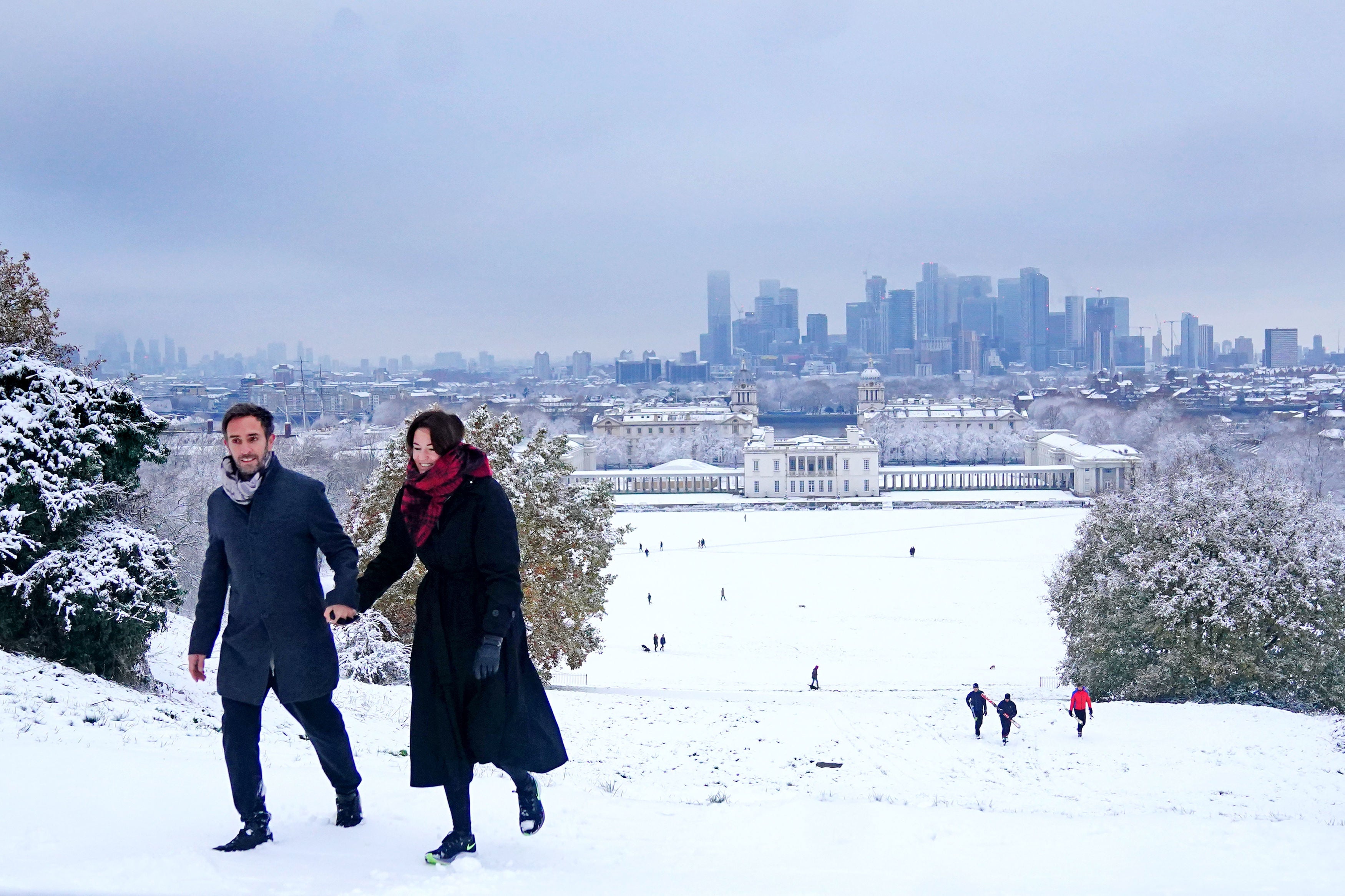 A couple walk through snow in Greenwich Park, southeast London
