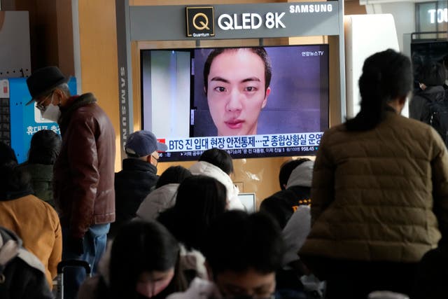 <p>A TV screen shows an image of BTS's member Jin with buzz cut, at the Seoul Railway Station in Seoul, South Korea, Monday, 12 December 2022</p>