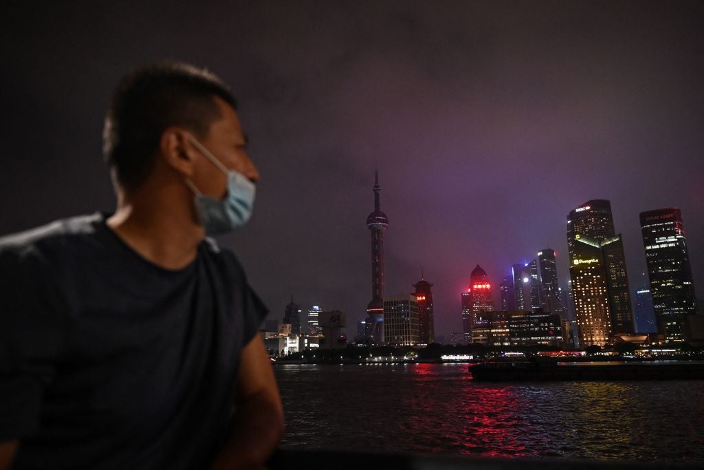 A man looks out from the Bund promenade along the Huangpu River as decorative lights are switched off as a measure to save energy in Shanghai