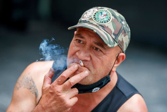 <p>A man sits while smoking in Auckland, New Zealand on 9 December 2021</p>
