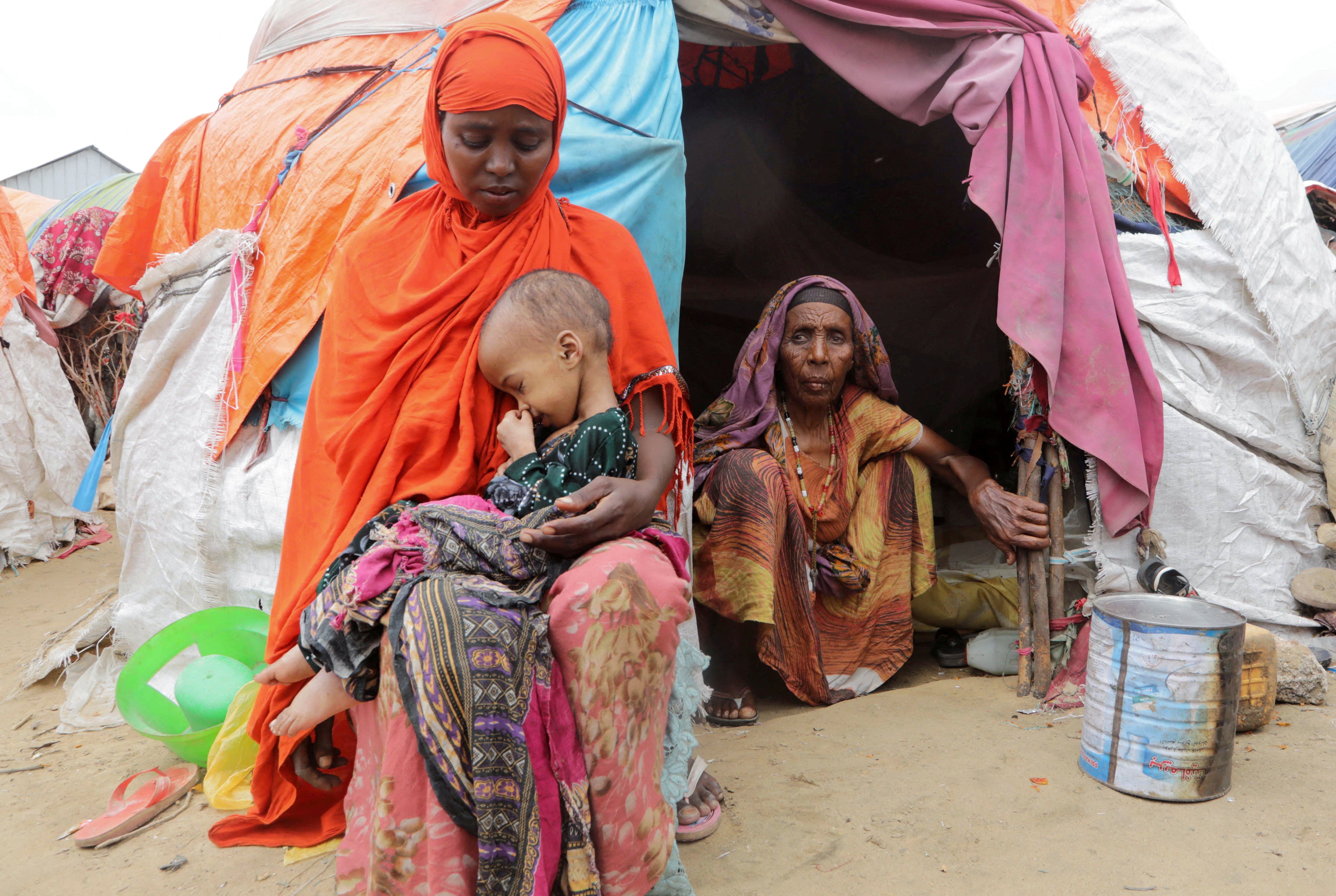 Buney Aayow Ibrahim, a Somali woman affected by the worsening drought due to failed rainy seasons, holds her child Sadia Salas Abdi, 3, as her grandmother Habiba Osman looks on, outside their makeshift shelter at the Alla Futo camp for internally displaced people, in the outskirts of Mogadishu