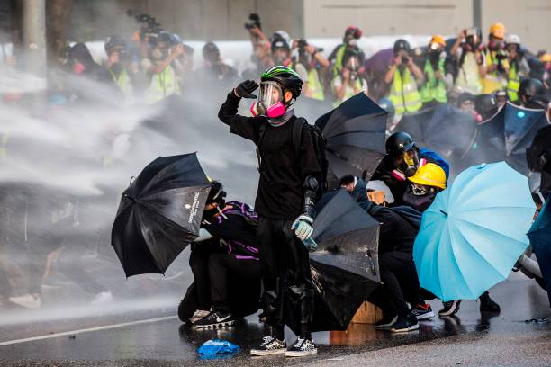 Pro-democracy protesters react as police fire water cannons outside government headquarters in Hong Kong in 2019