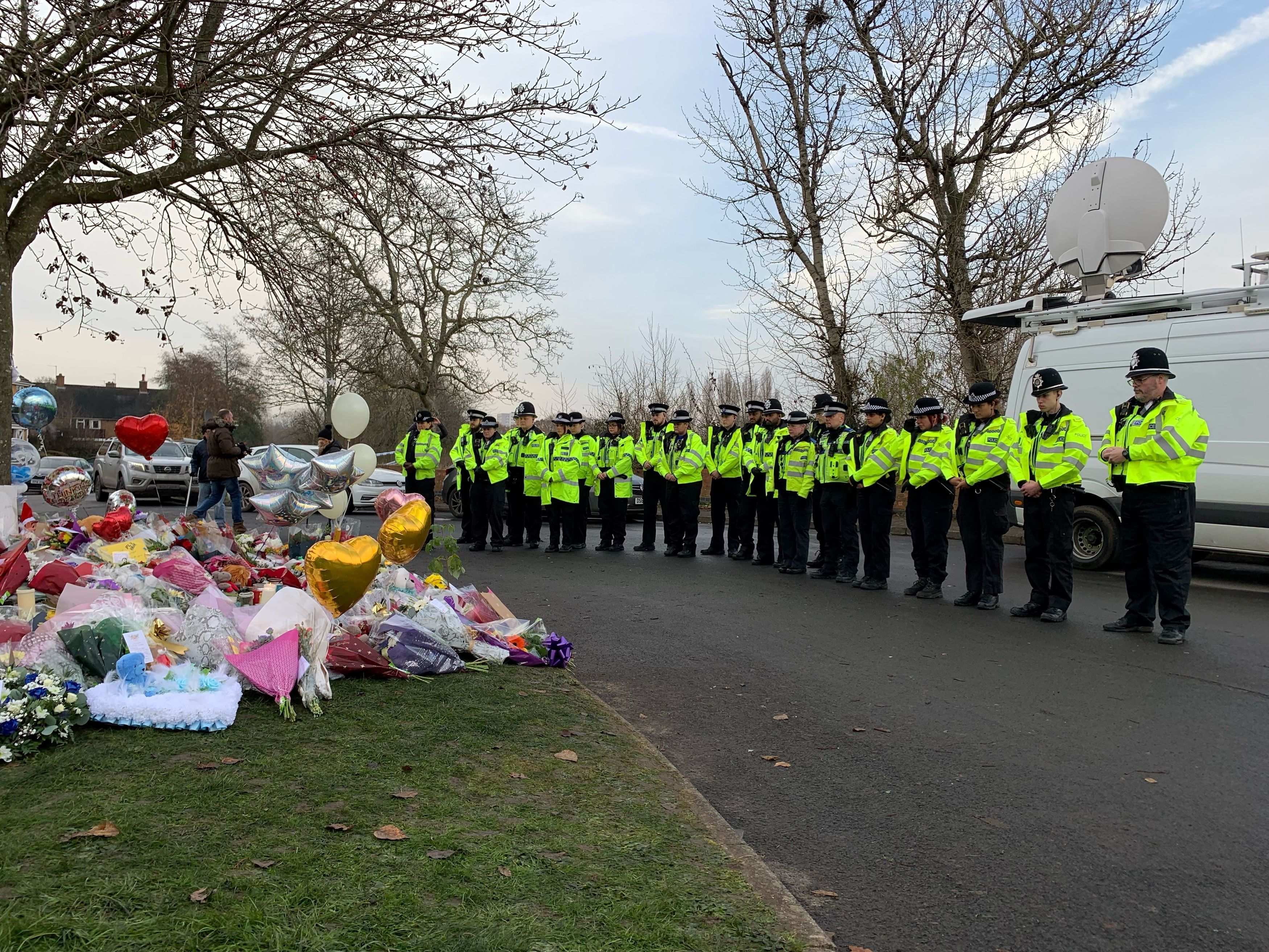 Officers from West Midlands Police lay flowers and stand in silence near the scene in Babbs Mill Park