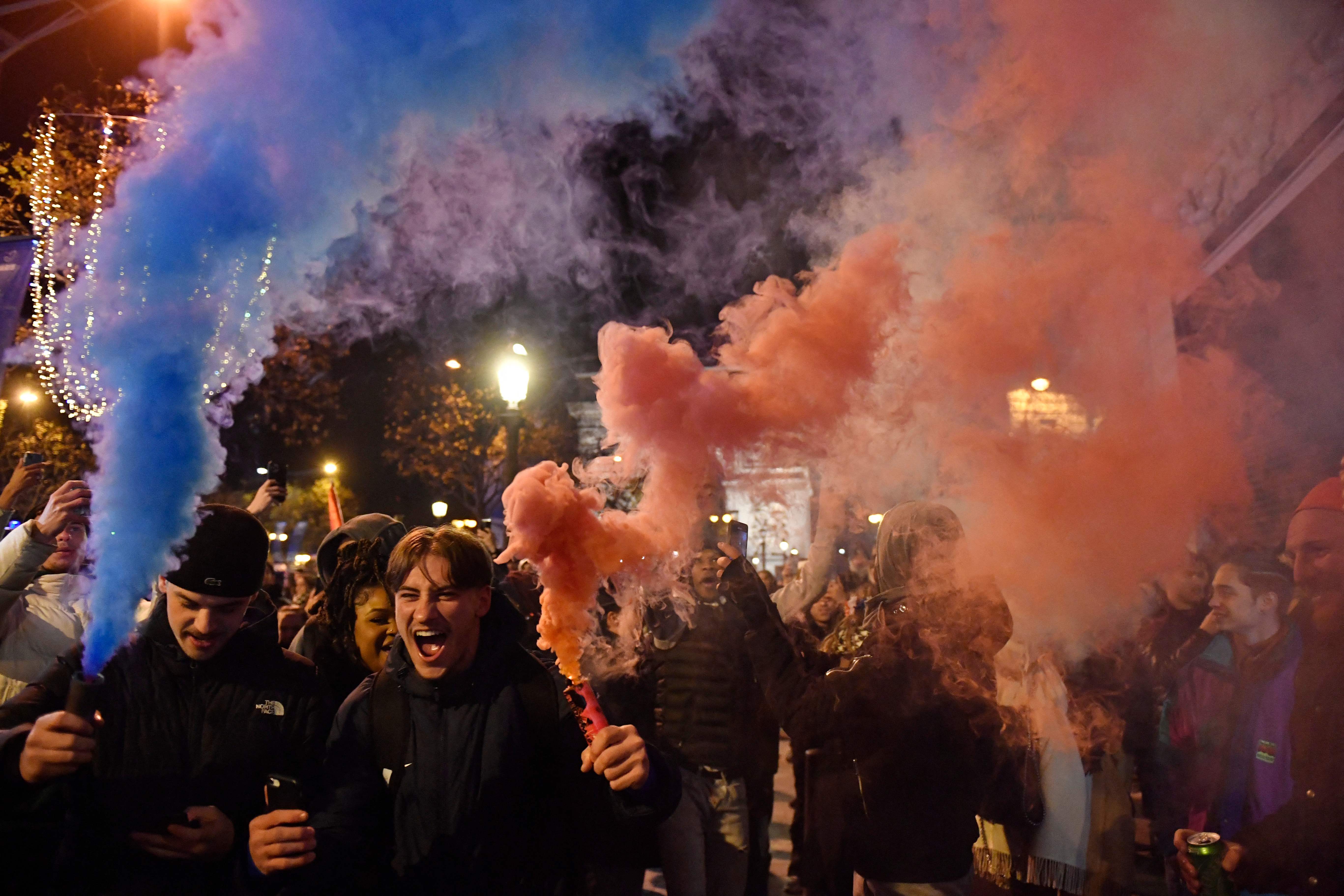 France fans hold smoke flares on the Champs-Elysees as they celebrate victory over Morocco on Wednesday night