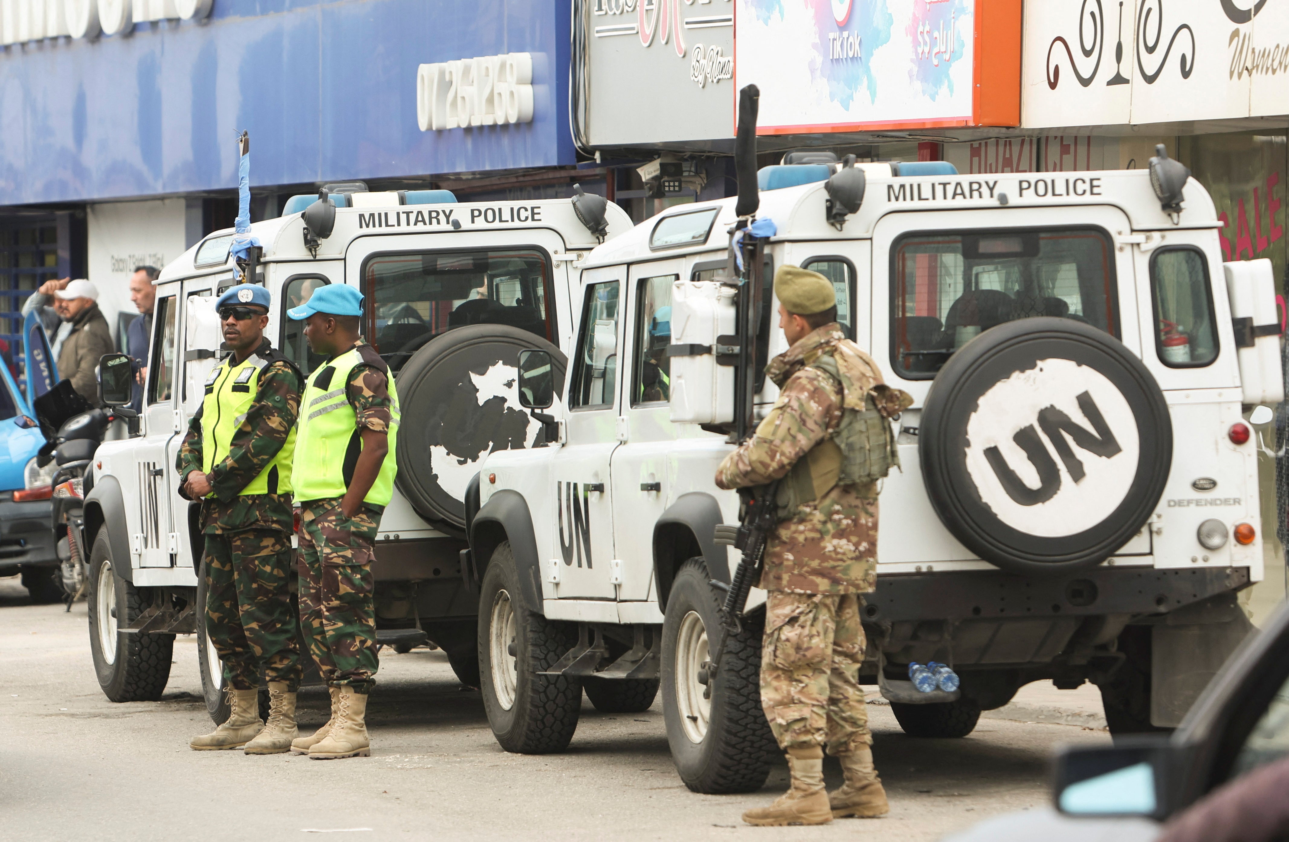 A Lebanese army member and United Nations peacekeepers (UNIFIL) stand next to a UNIFIL vehicles in Al-Aqbieh