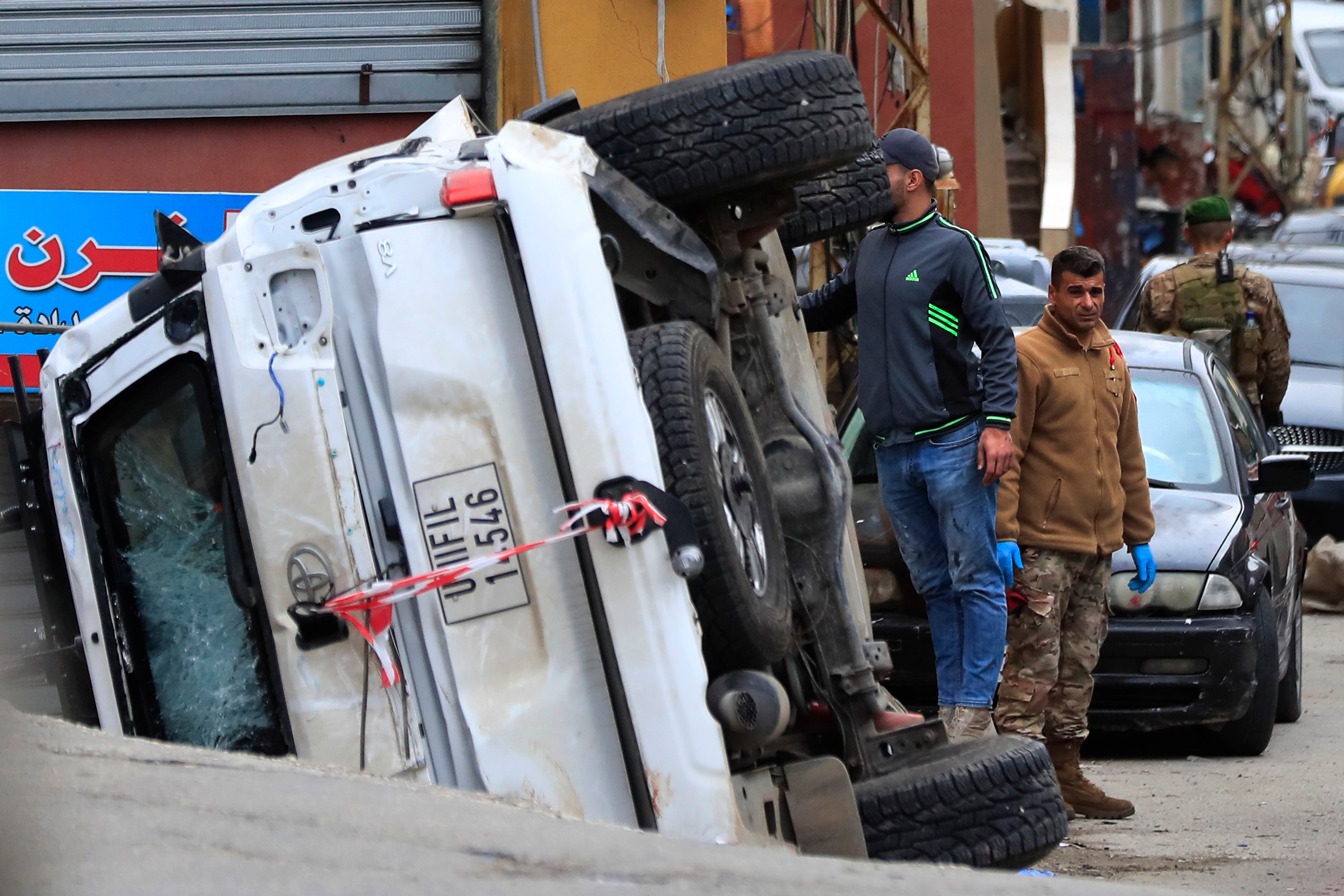 Lebanese soldiers stand next to a turned over UN peacekeeper vehicle at the scene where a UN peacekeeper convoy came under gunfire in Al-Aqbiya village, southern Lebanon