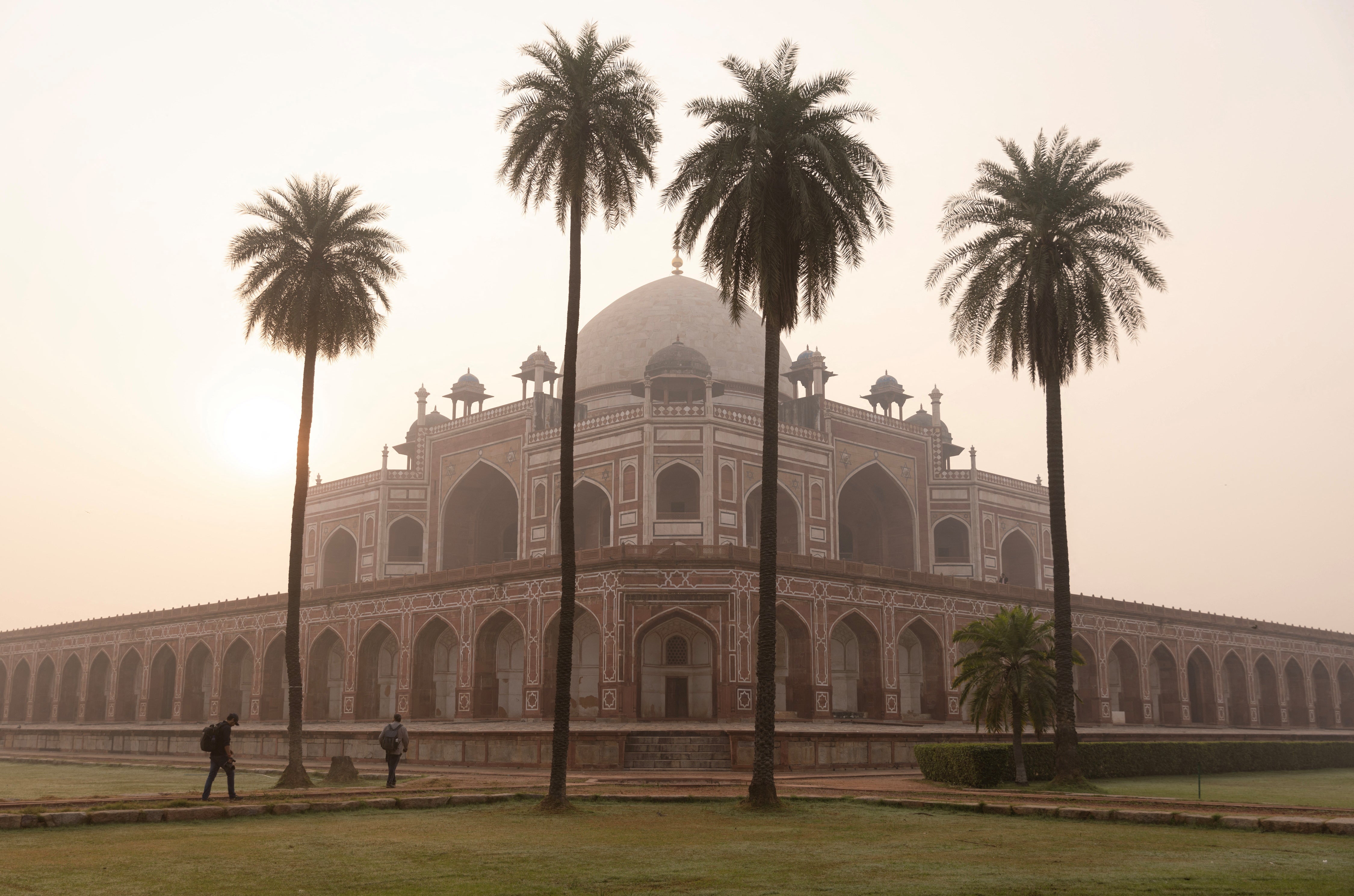 People walk in front of Humayun’s Tomb under morning smog
