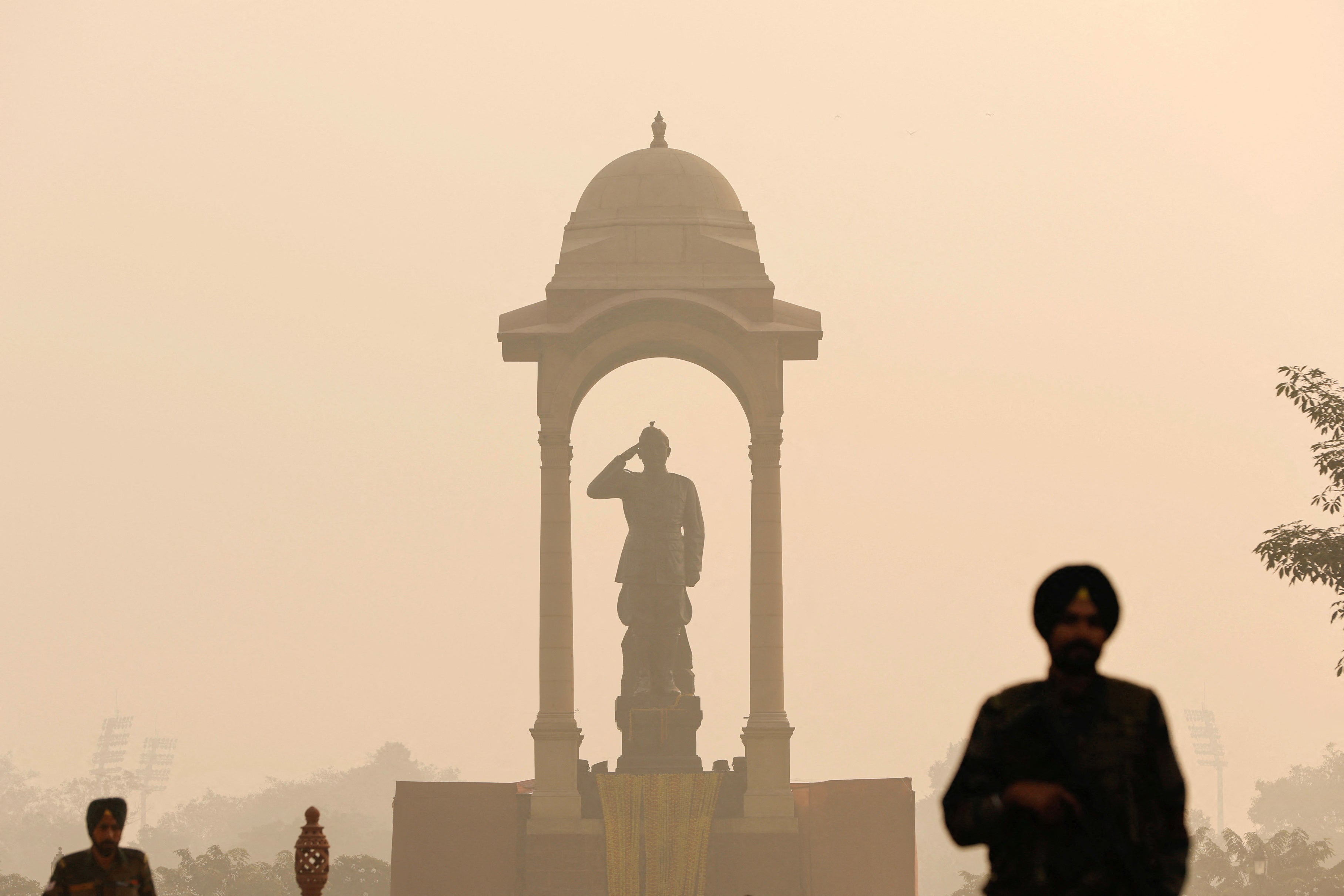 Soldiers stand guard during heavy smog under the statue of Subhas Chandra Bose behind the India Gate