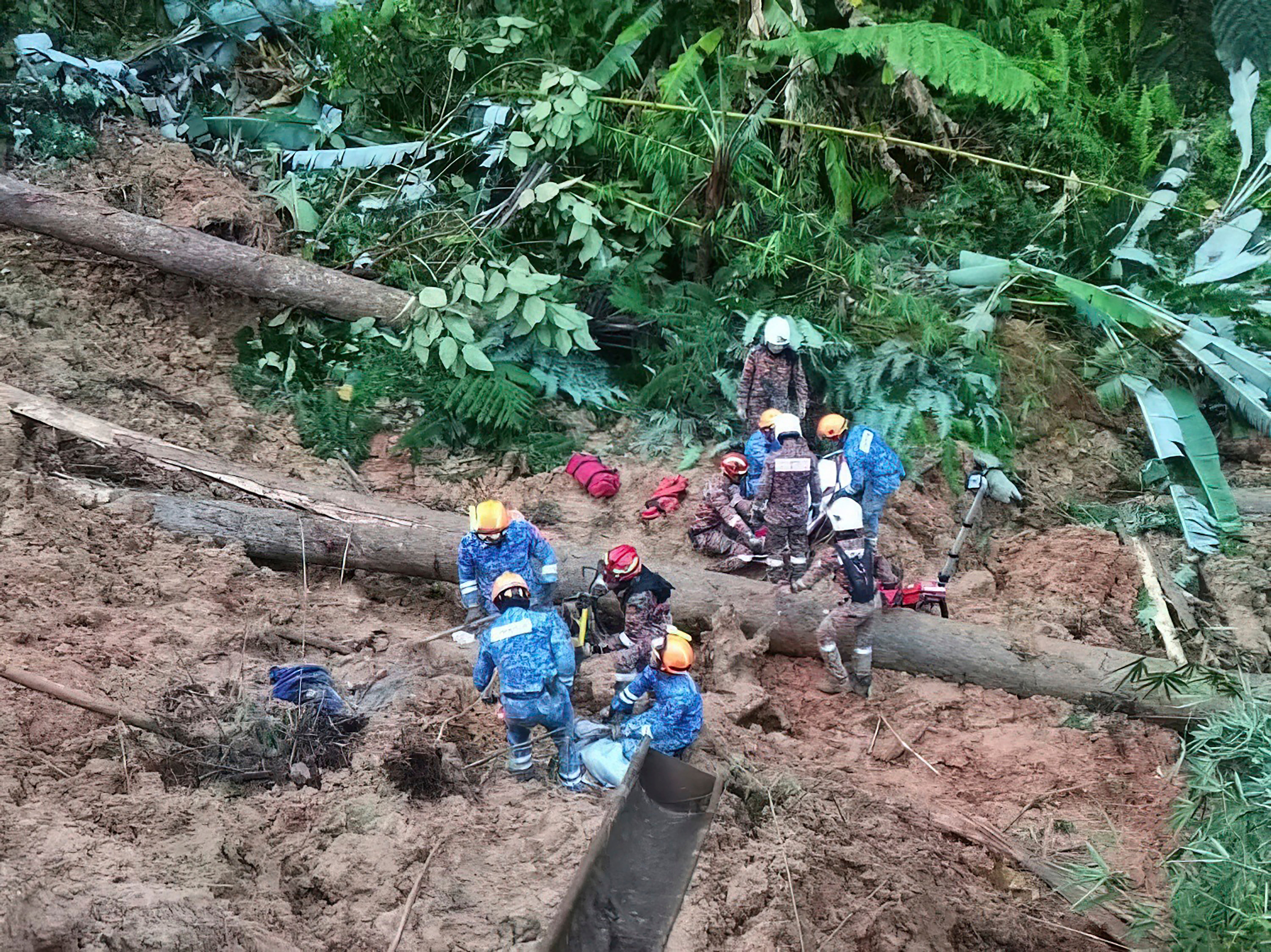 Civil Defense personnel search for missing persons after a landslide hit a campsite in Batang Kali, Malaysia