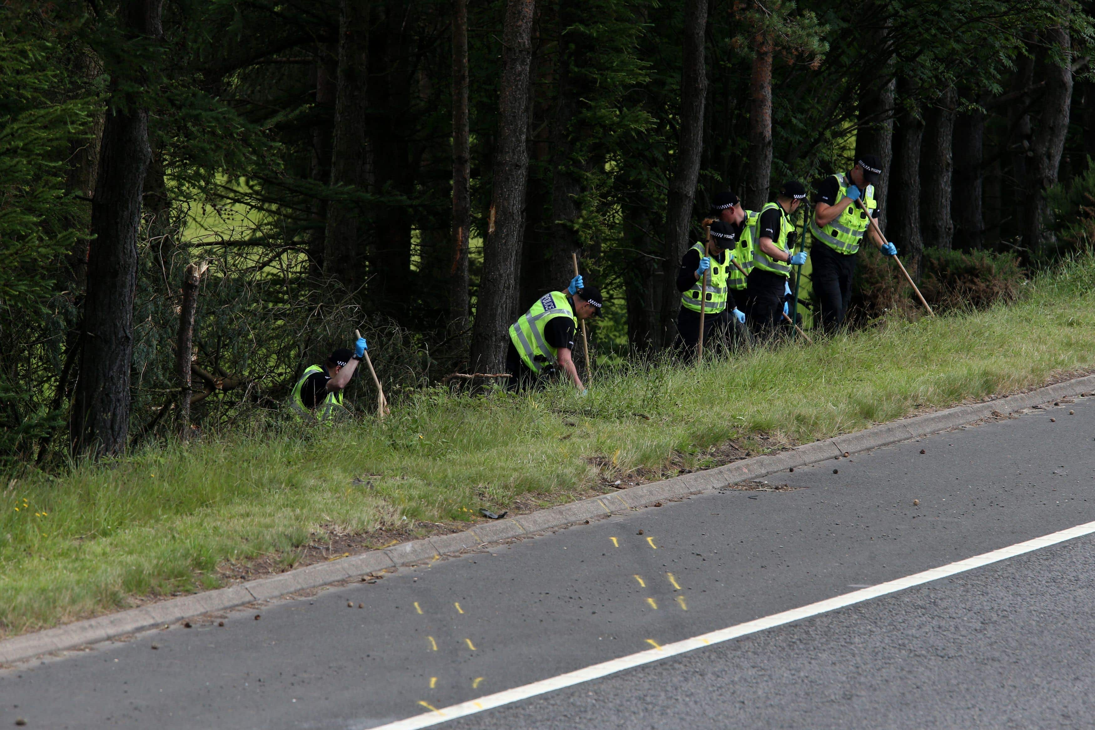 Police officers at the scene of the crash after the car was discovered (PA)