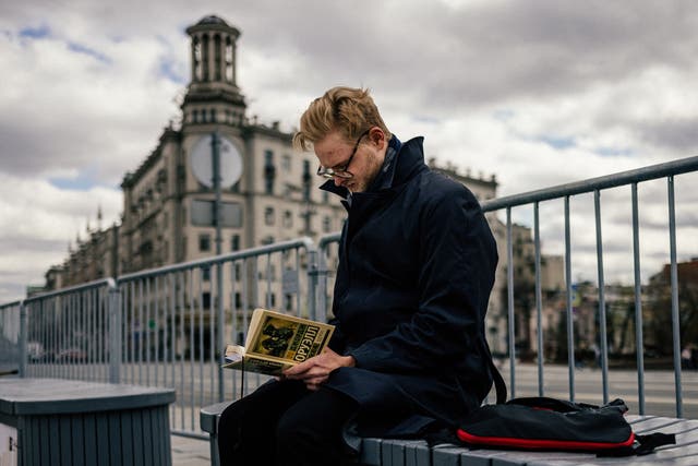 <p>A man reads a Russian translation of George Orwell’s book 1984 at Moscow’s Pushkinskaya Square</p>