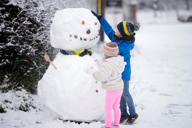 <p>Children build a snowman after the first significant snow fall in Cheshire this winter in Northwich, United Kingdom</p>