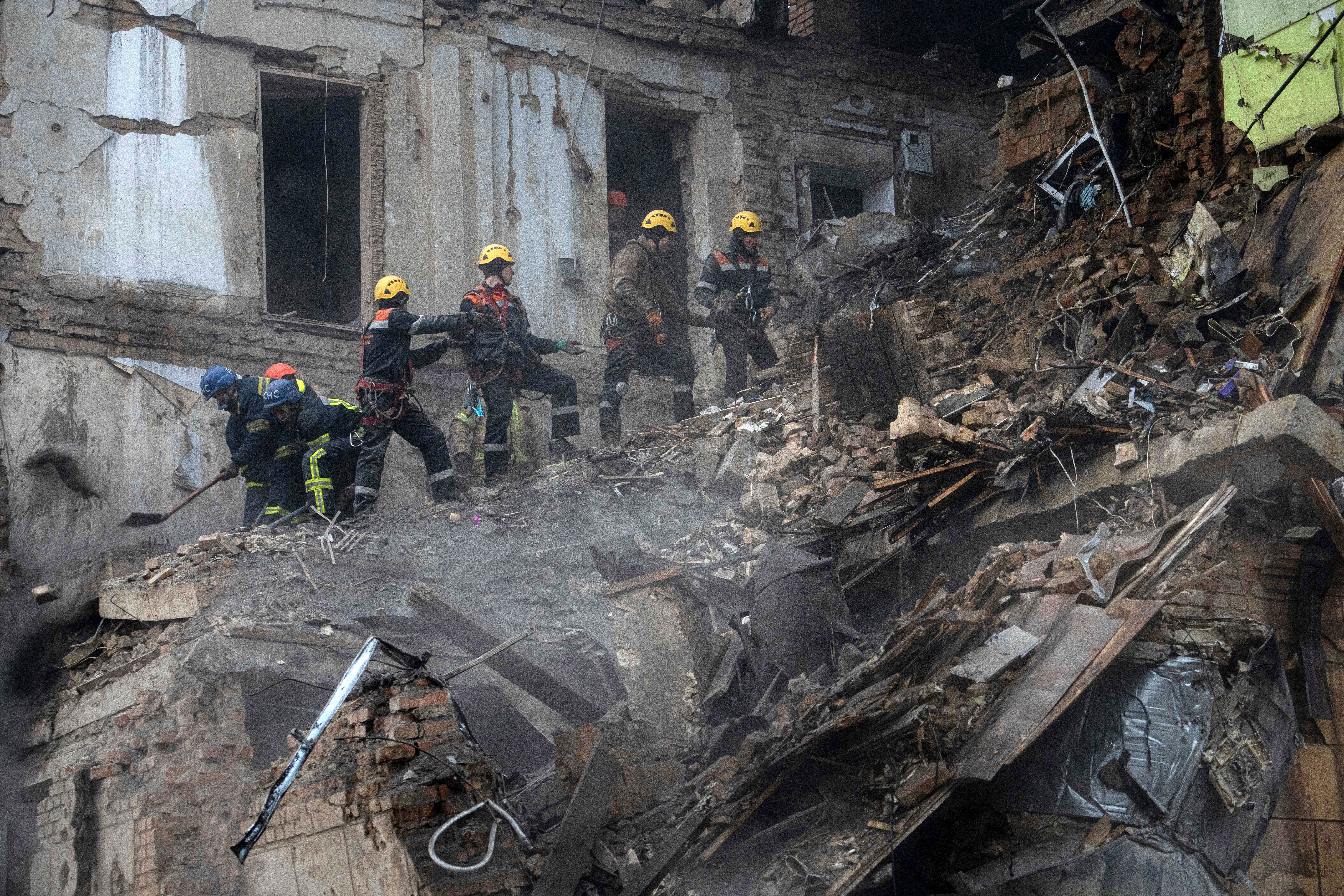 Ukrainian State Emergency Service firefighters clear the rubble at the building which was destroyed by a Russian attack in Kryvyi Rih