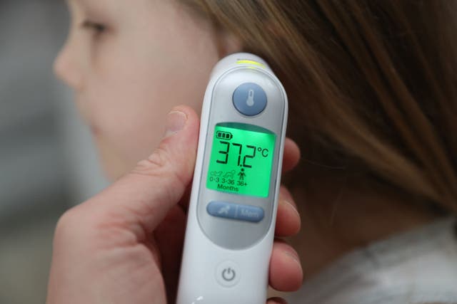 A child’s temperature is taken using an ear thermometer (Andrew Matthews/PA)