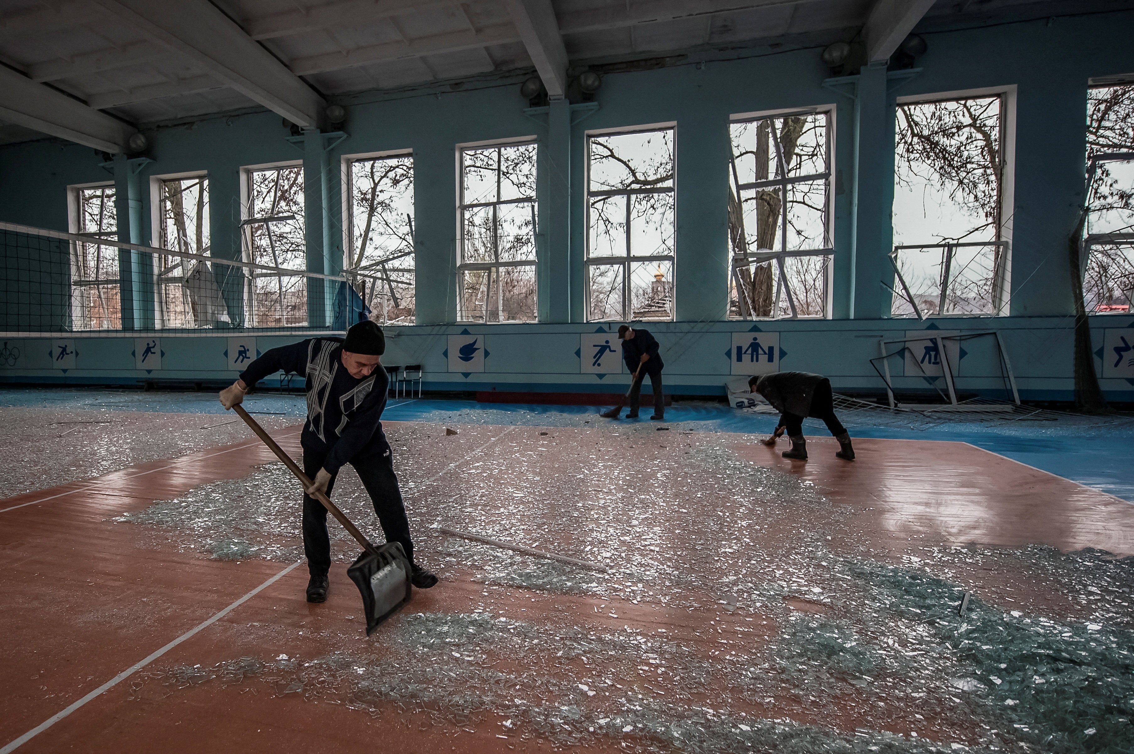 Local residents clean broken windows in a school gym damaged by a Russian military strike in Kramatorsk