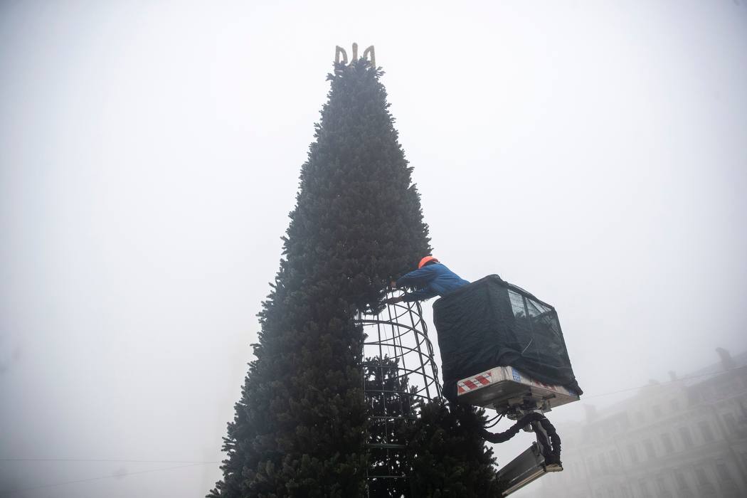A worker assembles the tree in Sofia Square, with the Ukrainian coat of arms in place of a star or angel