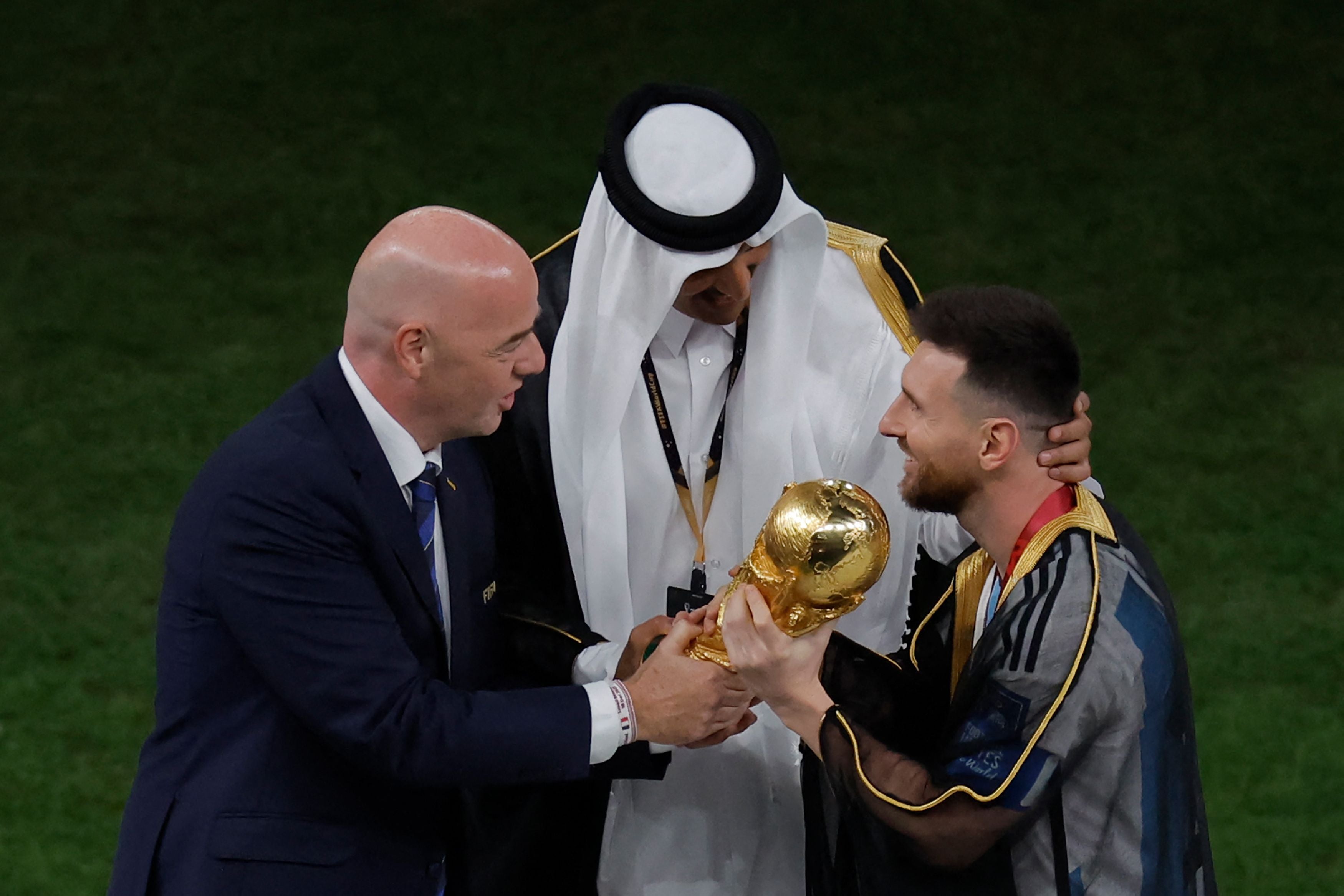 Lionel Messi receives the World Cup trophy from Fifa president Gianni Infantino as Qatar's emir, Sheikh Tamim bin Hamad al-Thani, watches on