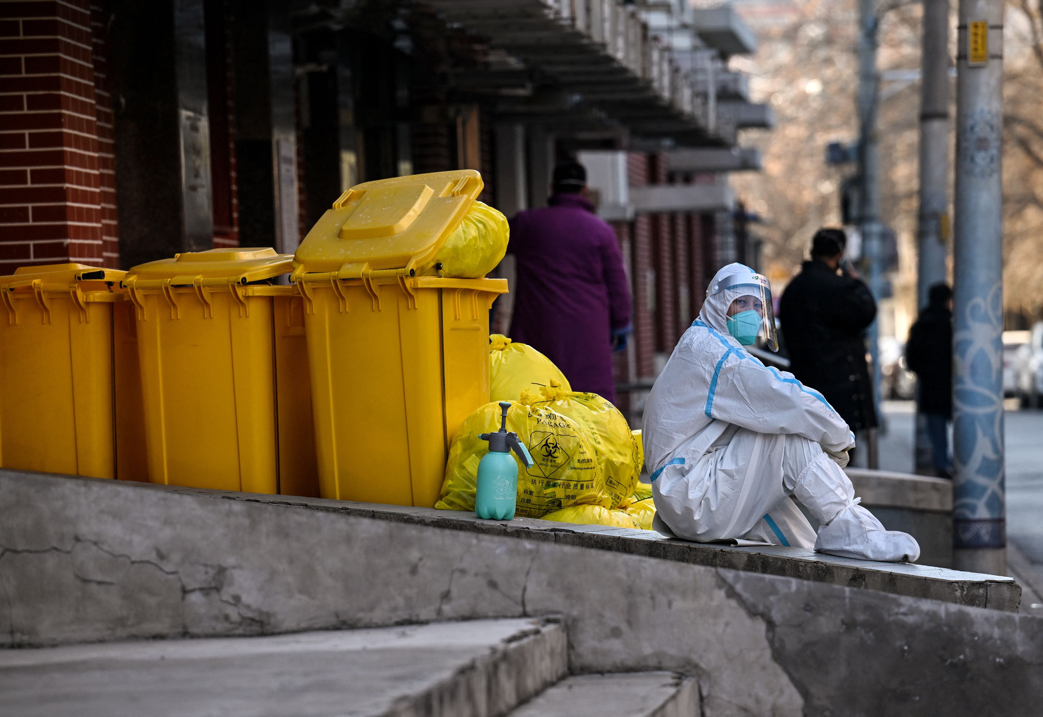 A worker wearing personal protective equipment (PPE) sits next to waste material outside a fever clinic amid the Covid-19 pandemic in Beijing on Monday