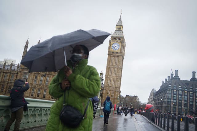A woman shelters beneath an umbrella as she walks in the rain along Westminster Bridge, central London (James Manning/PA)