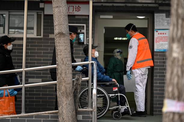 A man on a wheelchair assisted by emergency health workers arrives at a fever clinic amid the Covid-19 pandemic in Beijing on 20 December 2022