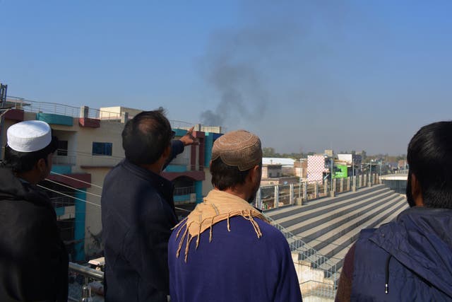 <p>Local residents watch smoke rising from a counter-terrorism center after security forces starting to clear the compound seized earlier by Pakistani Taliban militants in Bannu</p>