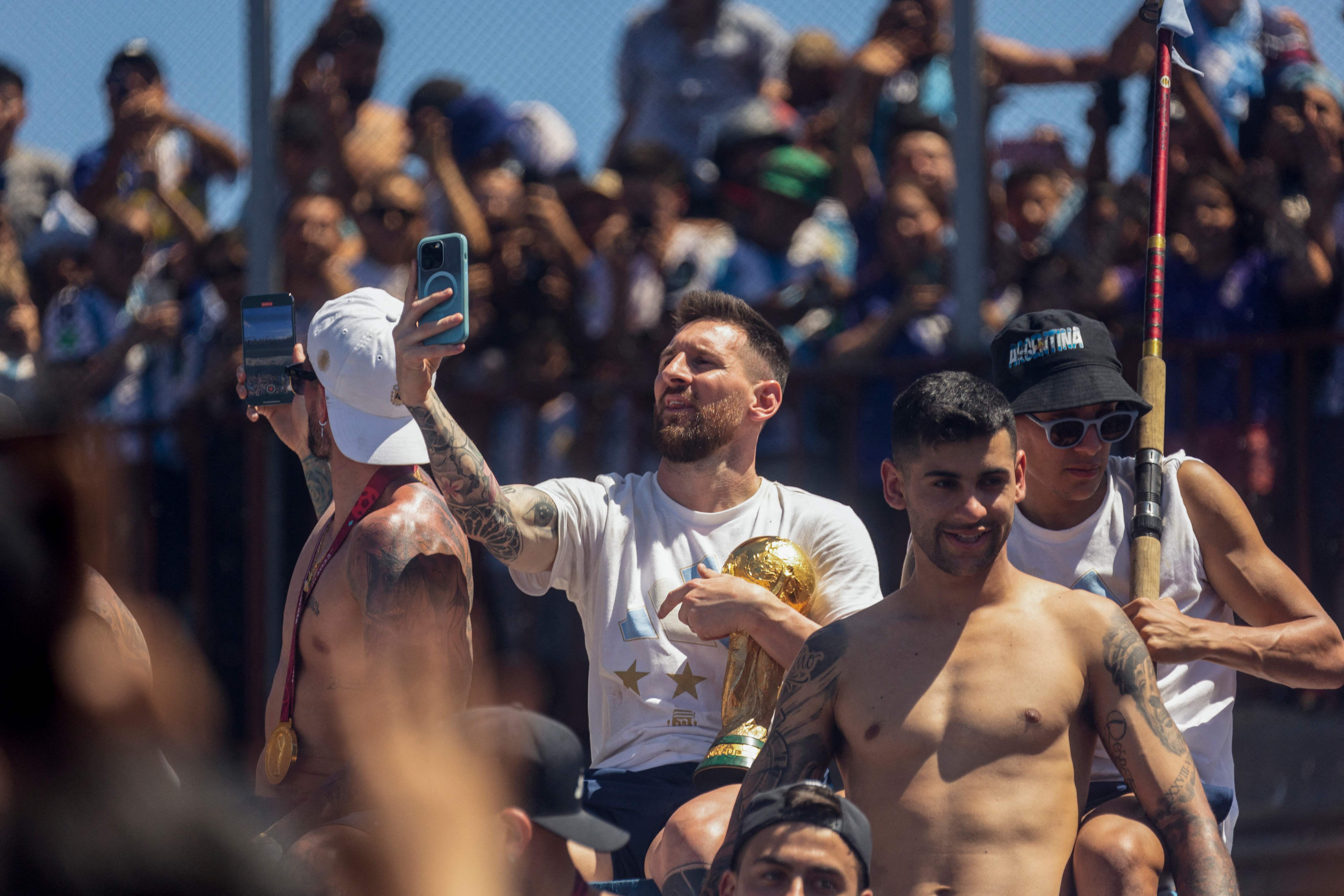 Lionel Messi takes pictures with his phone while celebrating on the bus
