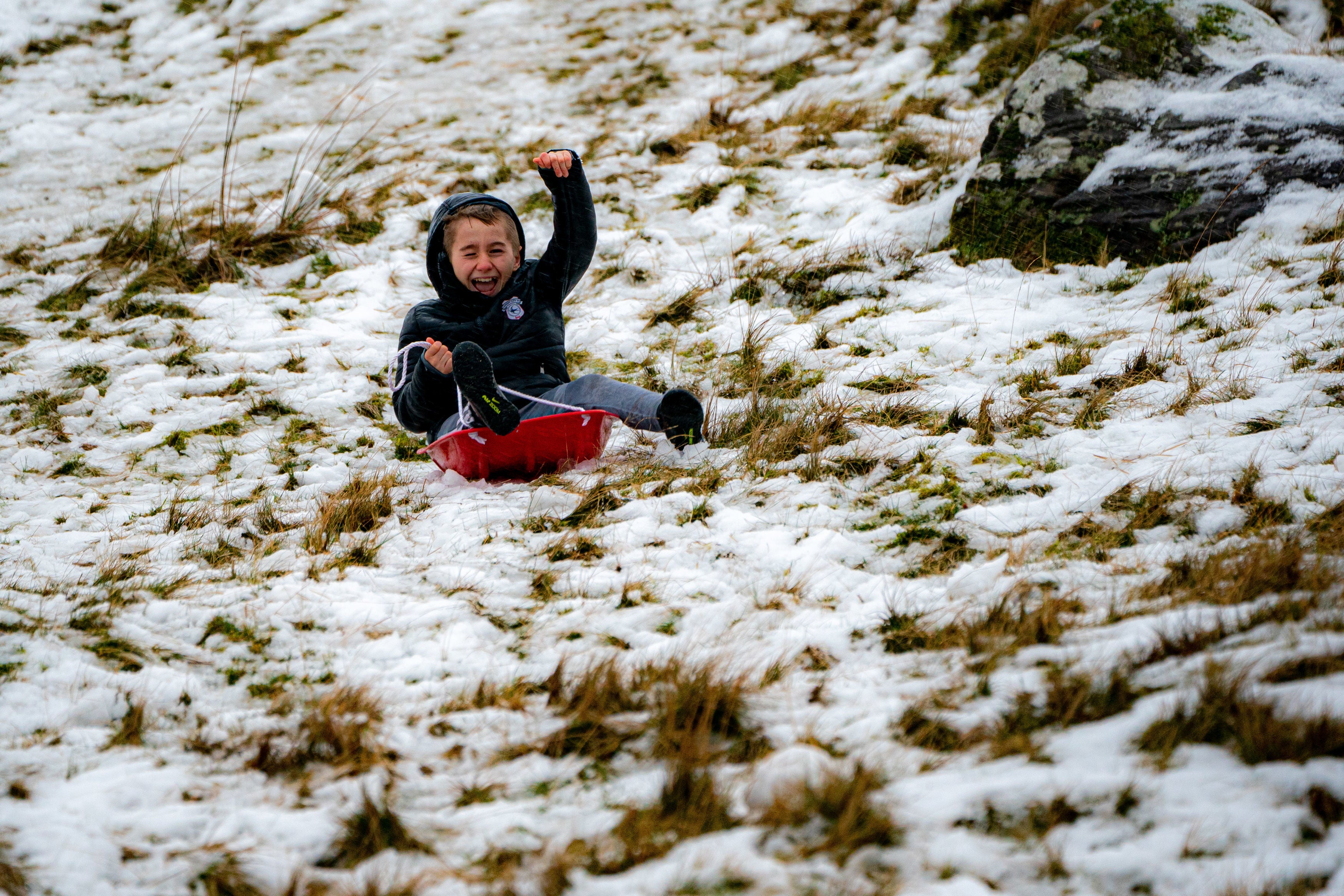 A sledger makes the most of the snow on an icy and snowy hill in the Brecon Beacons