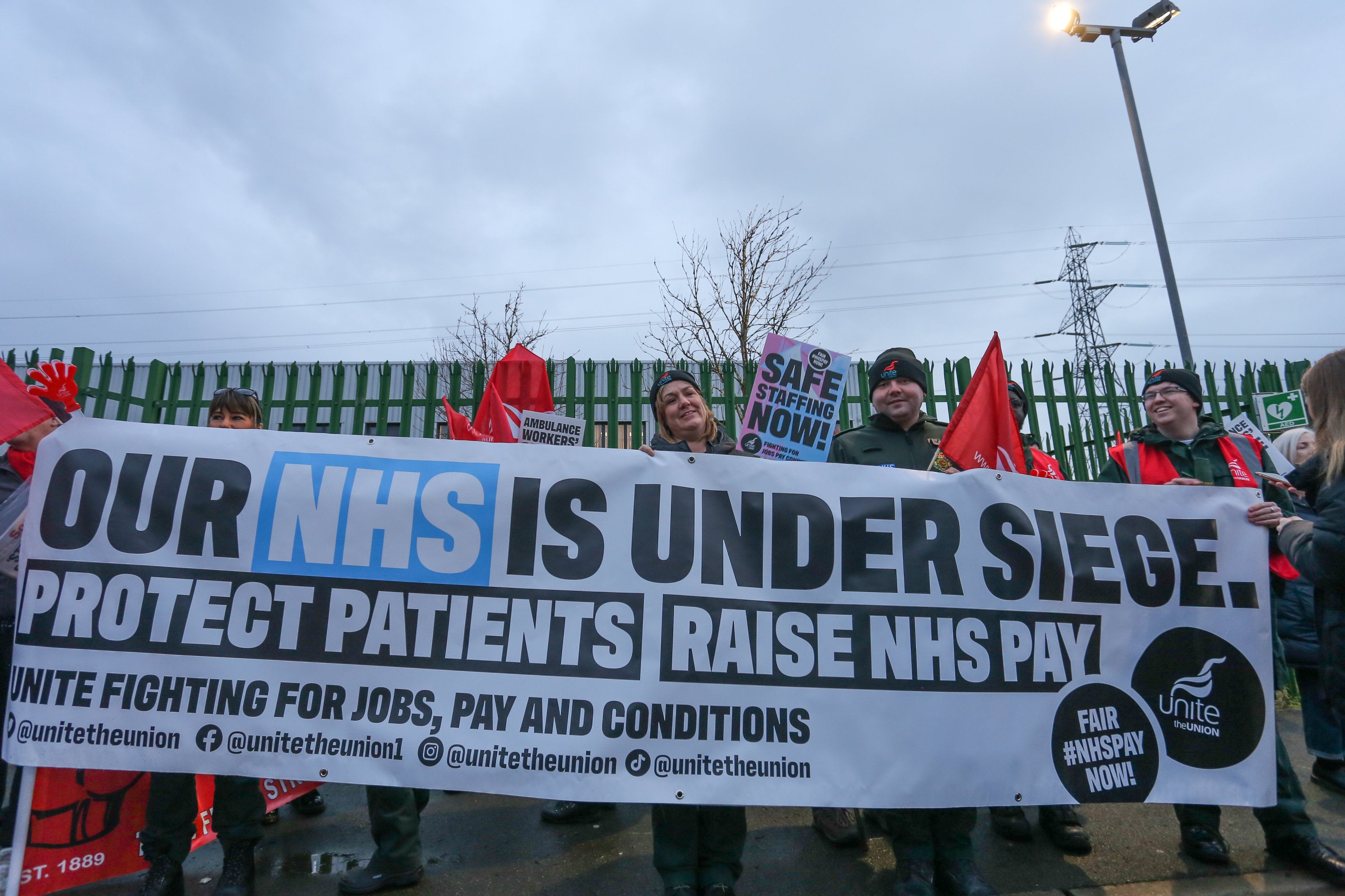 Unite members brandish a banner calling for a pay rise for NHS workers