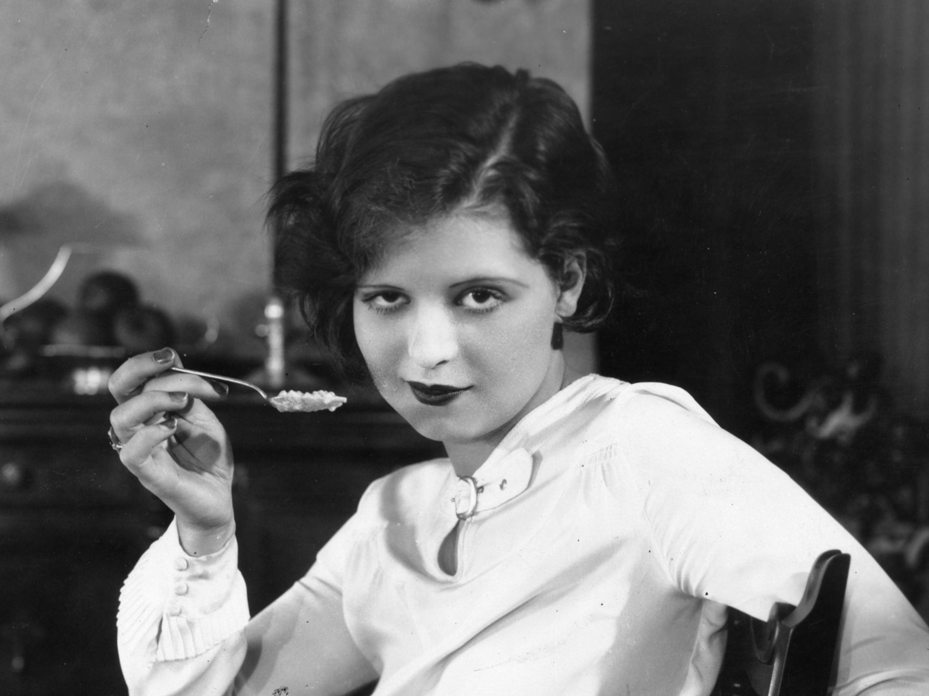 Bow poses with a spoonful of pudding, circa 1928