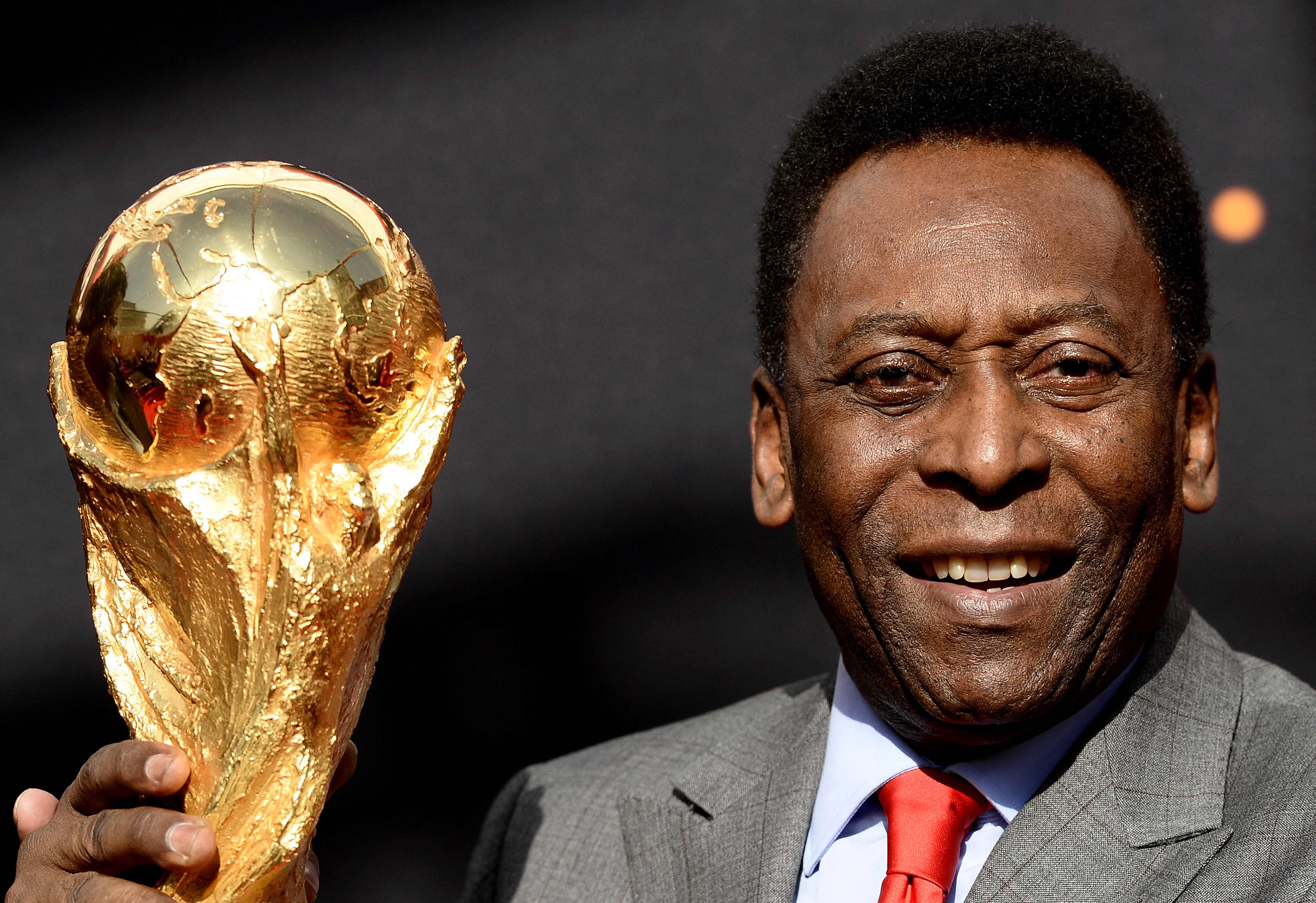 Pele poses with the World Cup trophy during a press conference, outside the Hotel de Ville in Paris in 2014