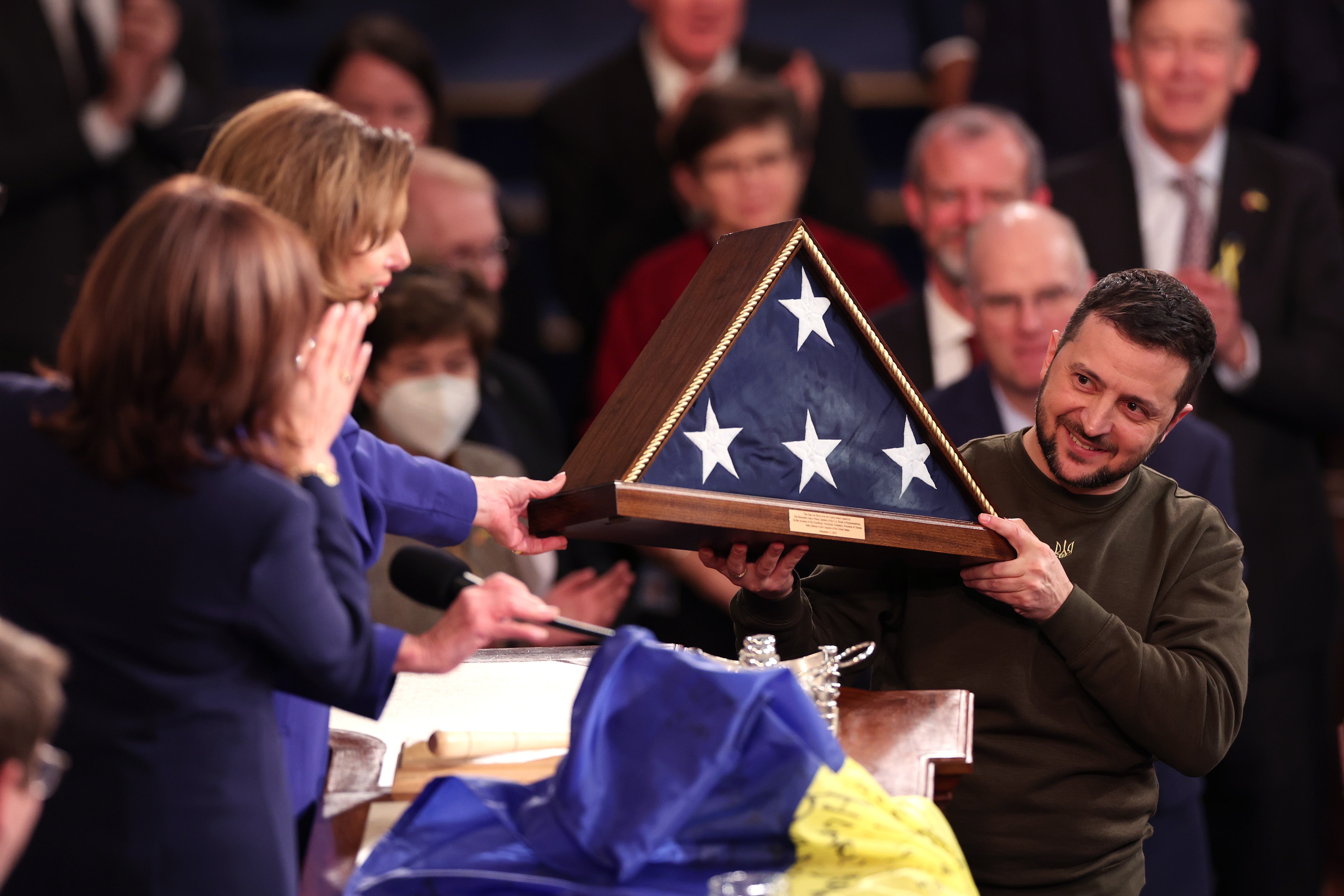 President of Ukraine Volodymyr Zelensky receives an American flag from U.S. Speaker of the House Nancy Pelosi (D-CA) and Vice President Kamala Harris as he addresses a joint meeting of Congress in the House Chamber of the U.S. Capitol on December 21, 2022 in Washington, DC