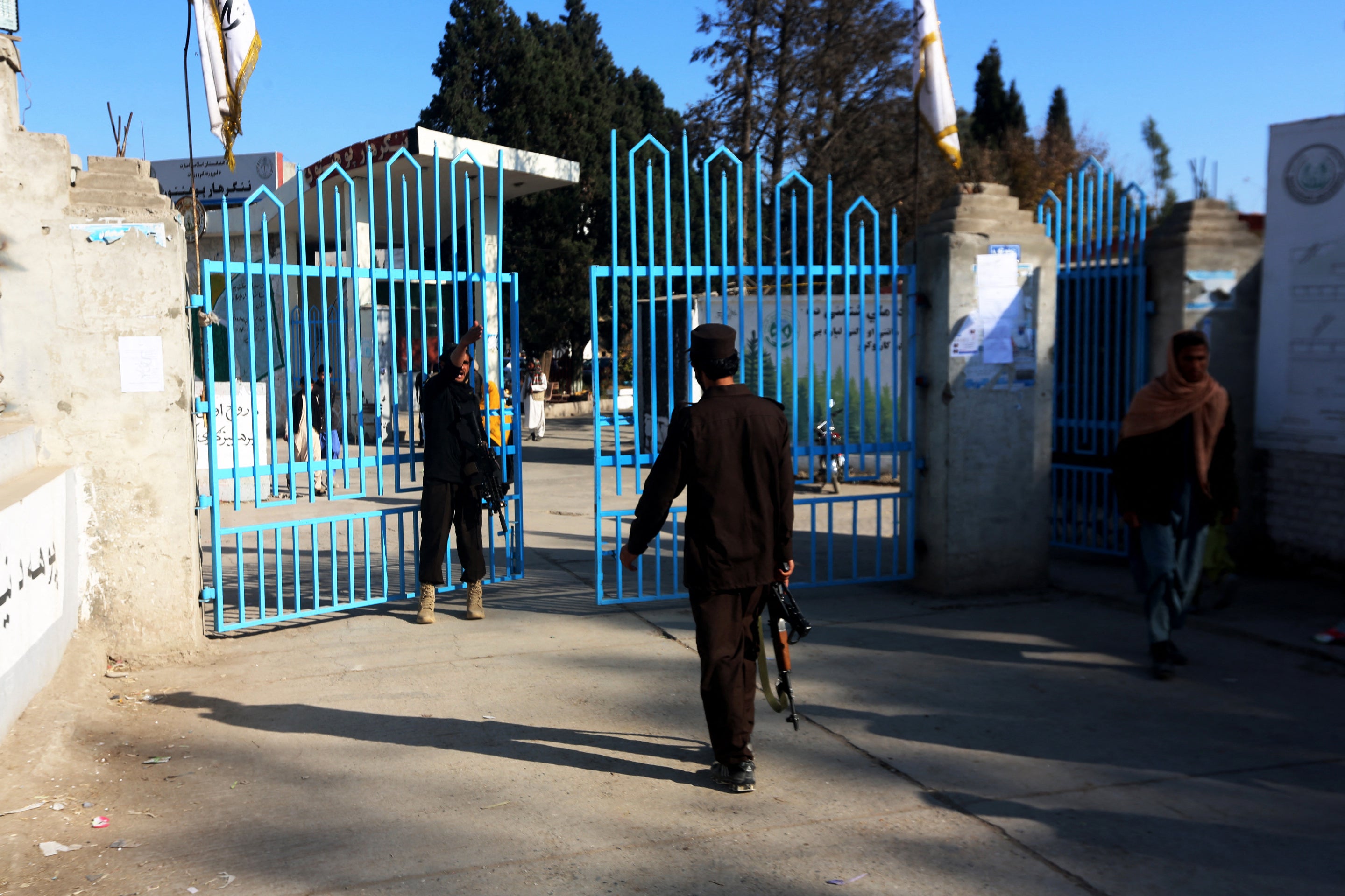 Taliban security personnel stand guard at the entrance gate of a university in Jalalabad on 21 December