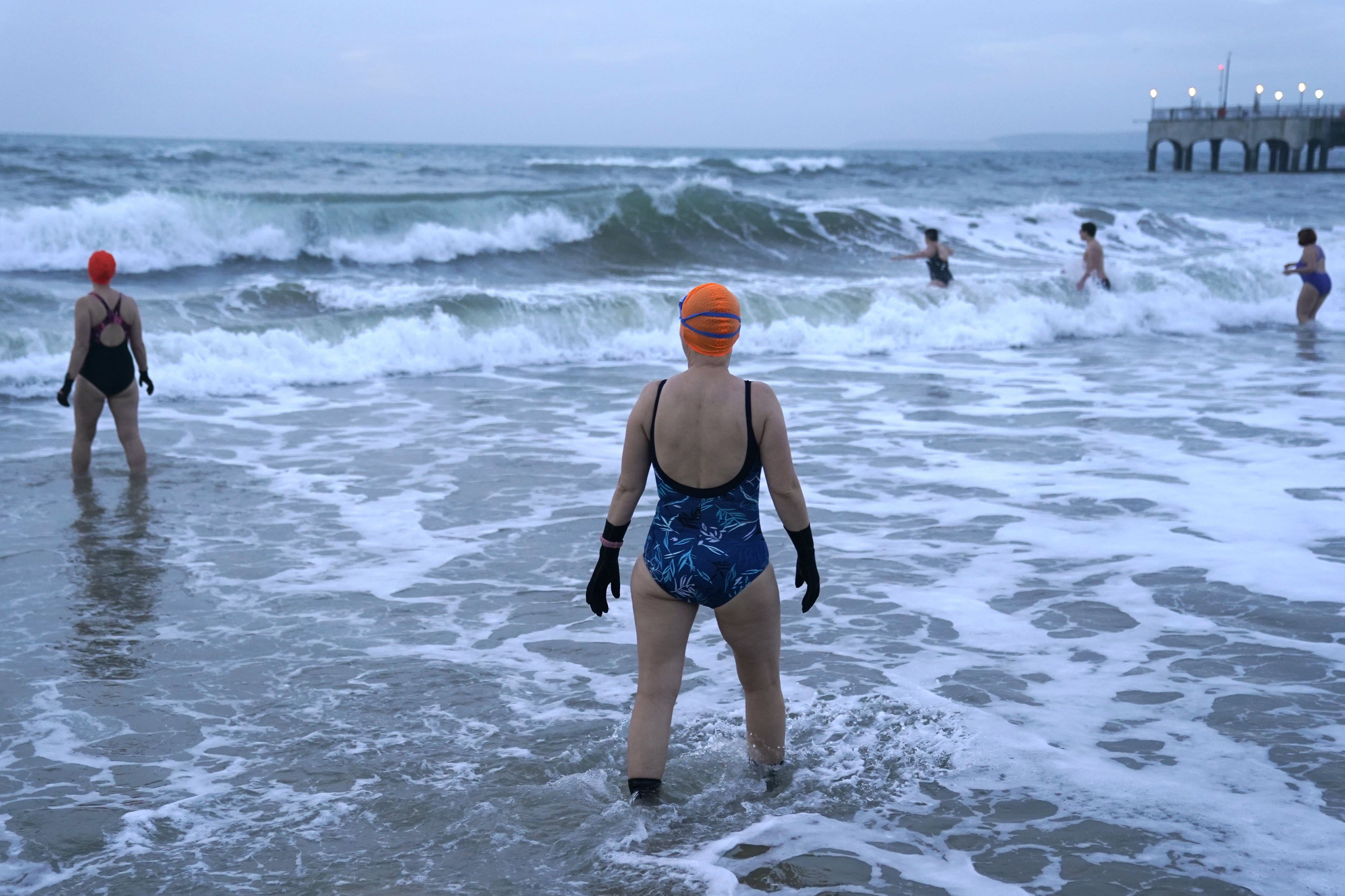 Swimmers make their way out to sea as the sun begins to rise over Boscombe beach in Dorset. Picture date: Saturday January 1, 2022.