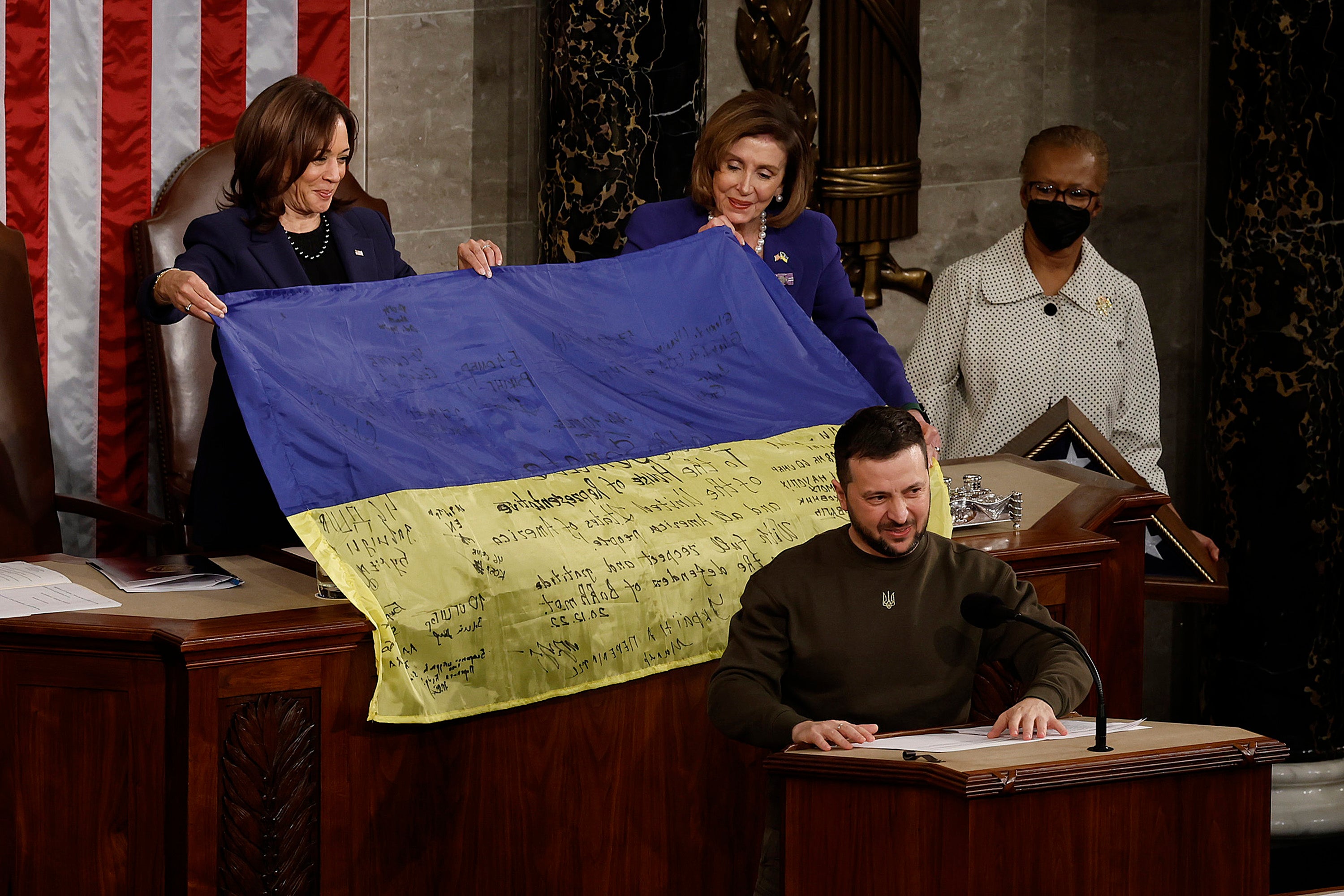Nancy Pelosi and vice president Kamala Harris hold a Ukrainian flag signed by members of its military, given to them by Volodymyr Zelensky
